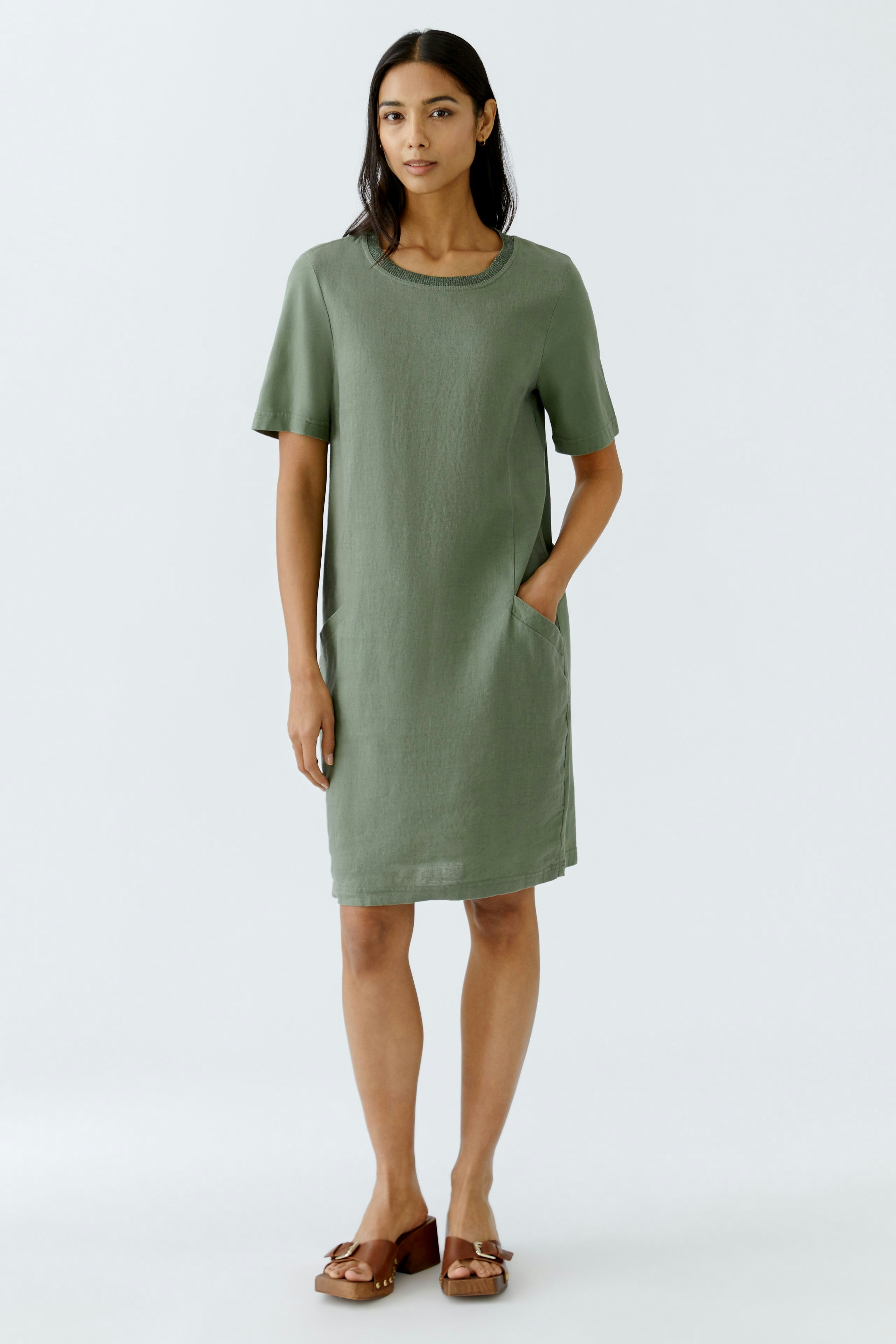 Casual women's dress: A woman in a green short-sleeve dress with pockets, perfect for warm days.
