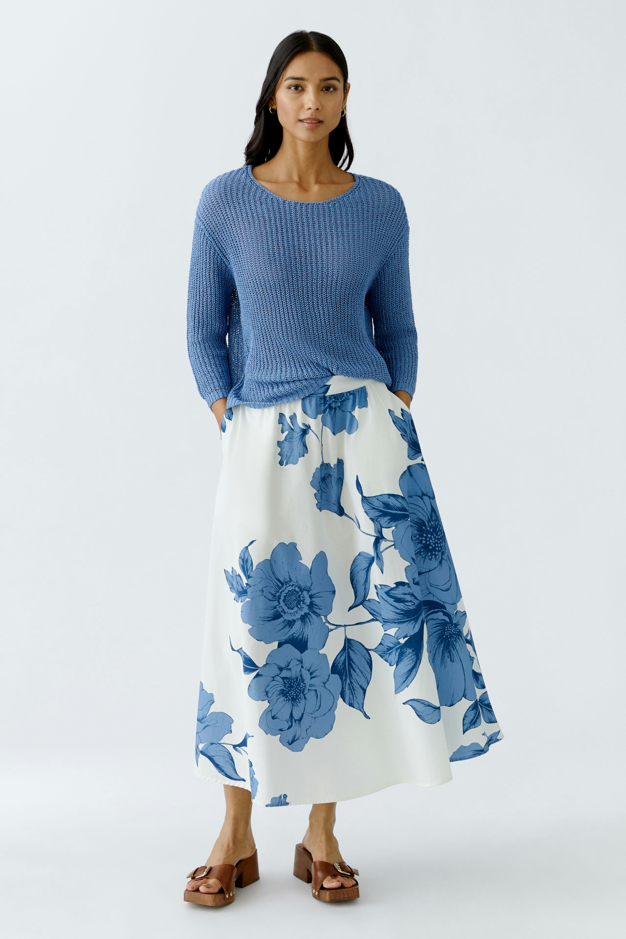 Elegant A-line skirt: Woman in a floral skirt with blue flowers, paired with a cozy blue pullover.
