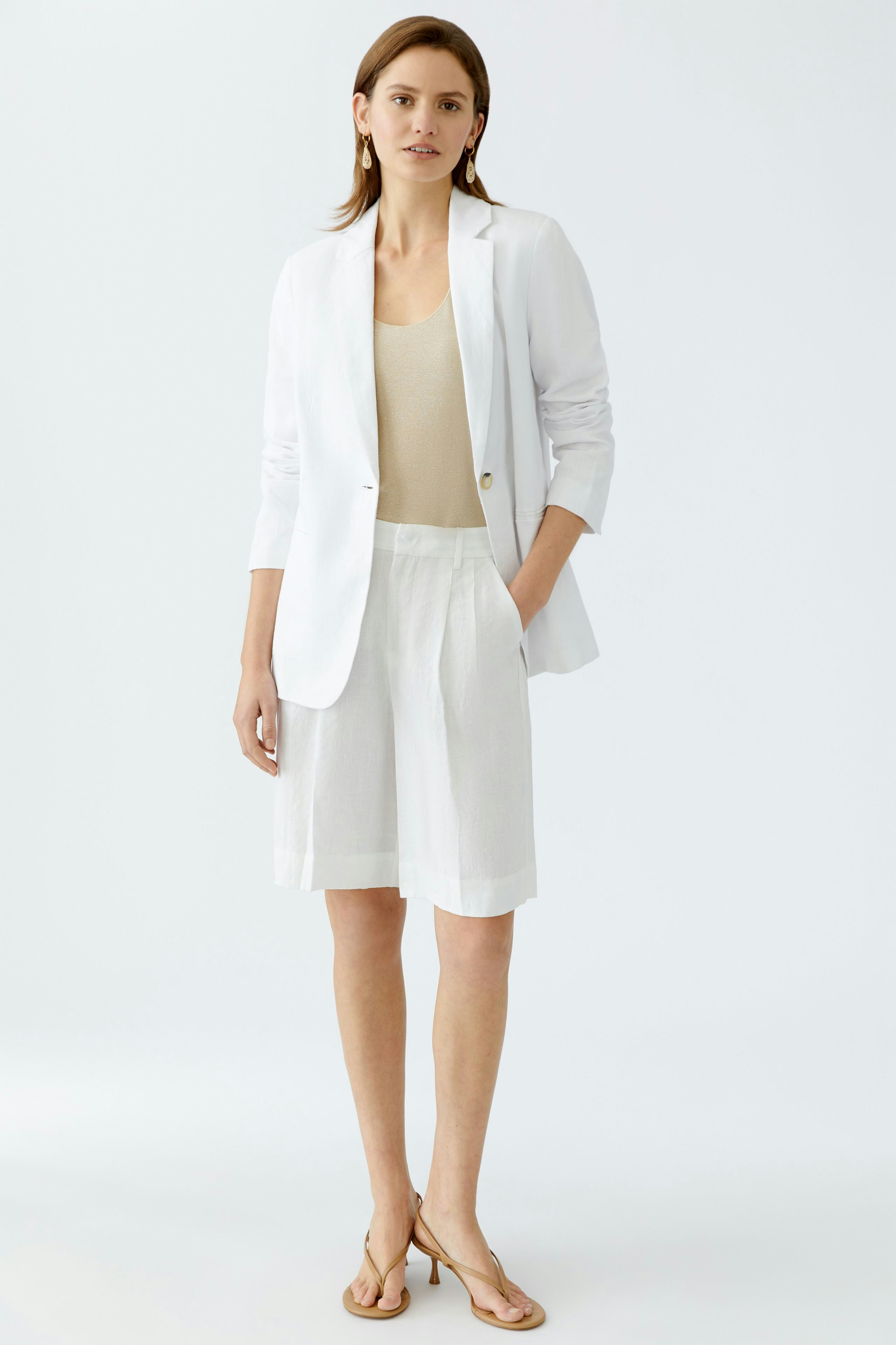 Elegante Damen-Bermuda: Frau in weißer Bermuda und Blazer, kombiniert mit einem beigen Top.