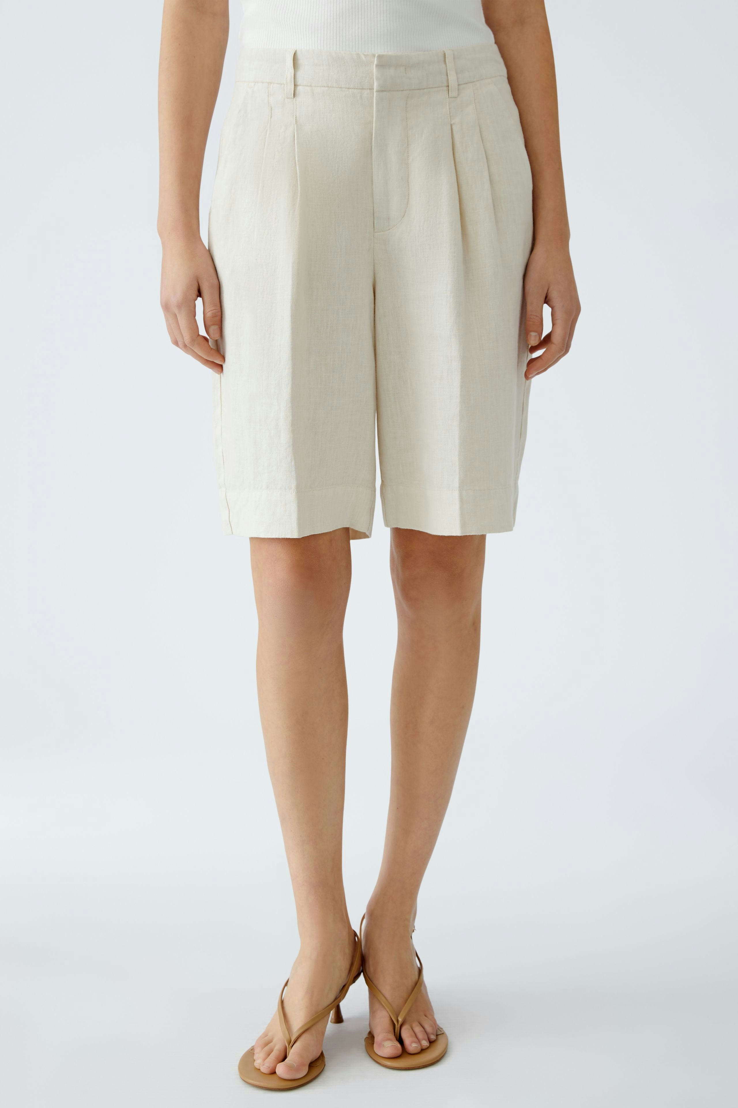 Elegante Damen-Bermuda: Frau in beigen, lässigen Shorts mit weitem Schnitt und seitlichen Taschen.