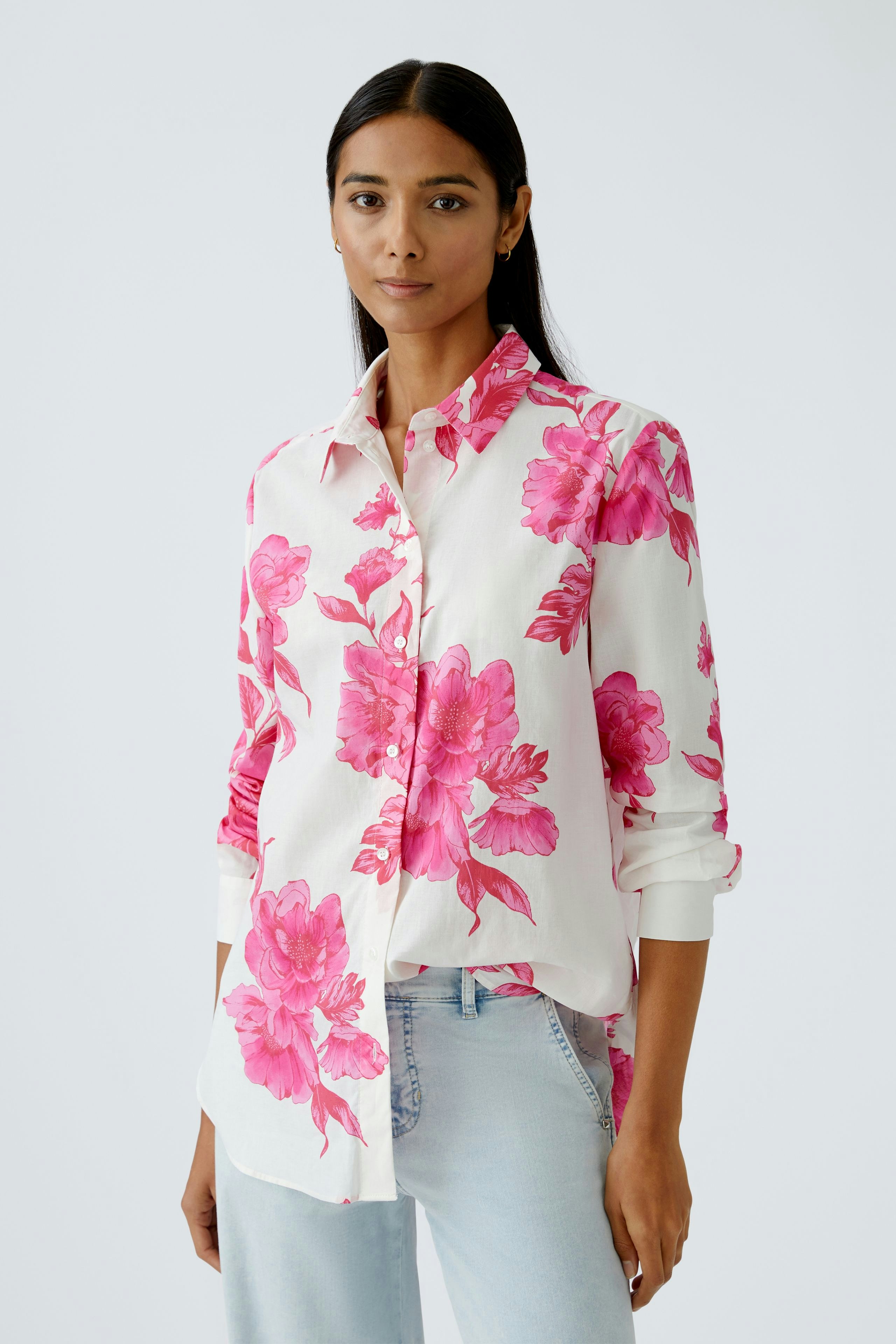 Damen-Bluse mit buntem Blumenmuster: Frau trägt eine lockere, blütenweiße Bluse mit pinken Blumen.