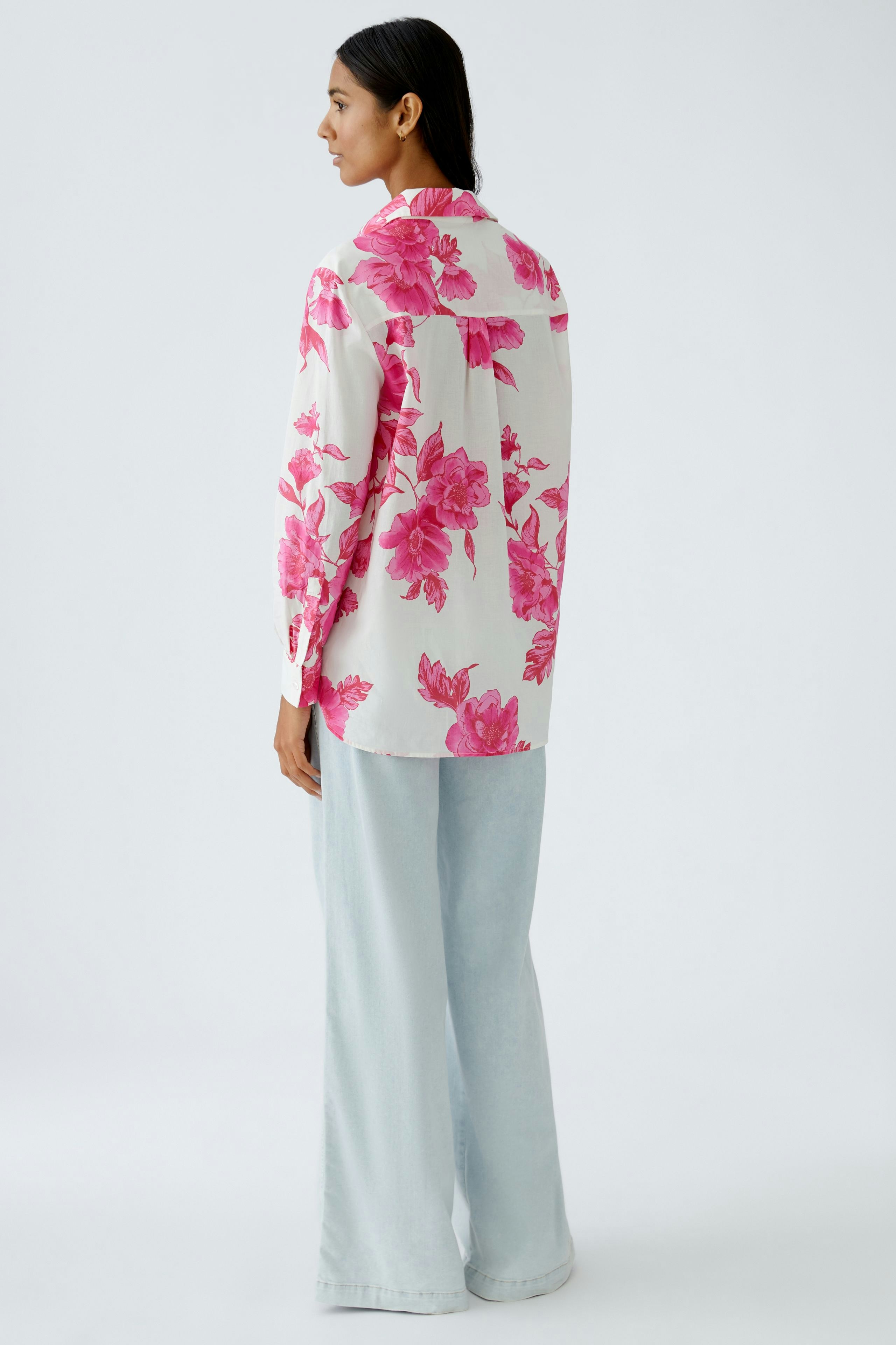 Damen-Bluse mit buntem Blumenmuster: Frau in blumiger Bluse und lässigen Hosen von hinten.