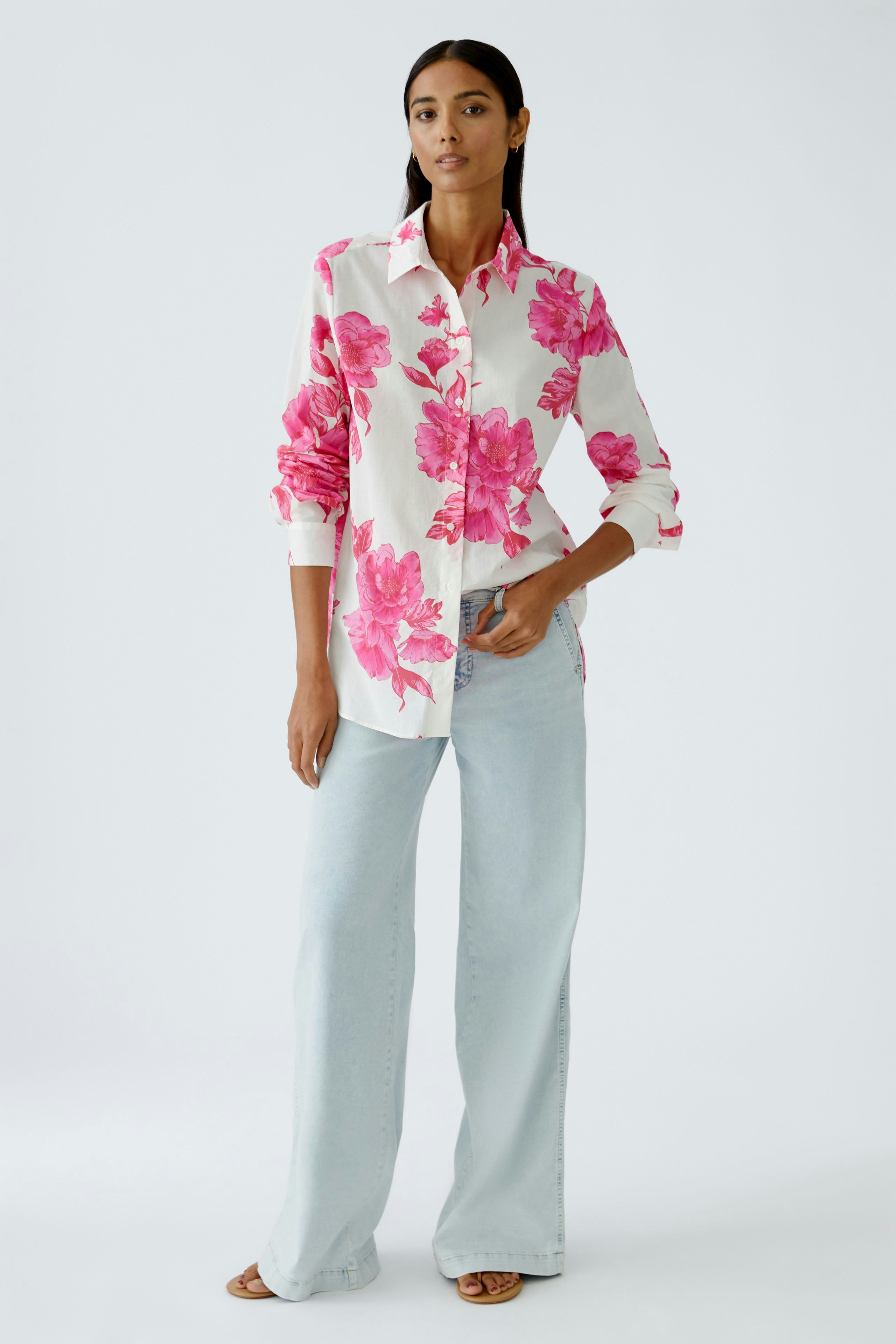 Damen-Bluse mit buntem Blumenmuster: Frau trägt eine lockere, blumige Bluse zu hellblauen Jeans.