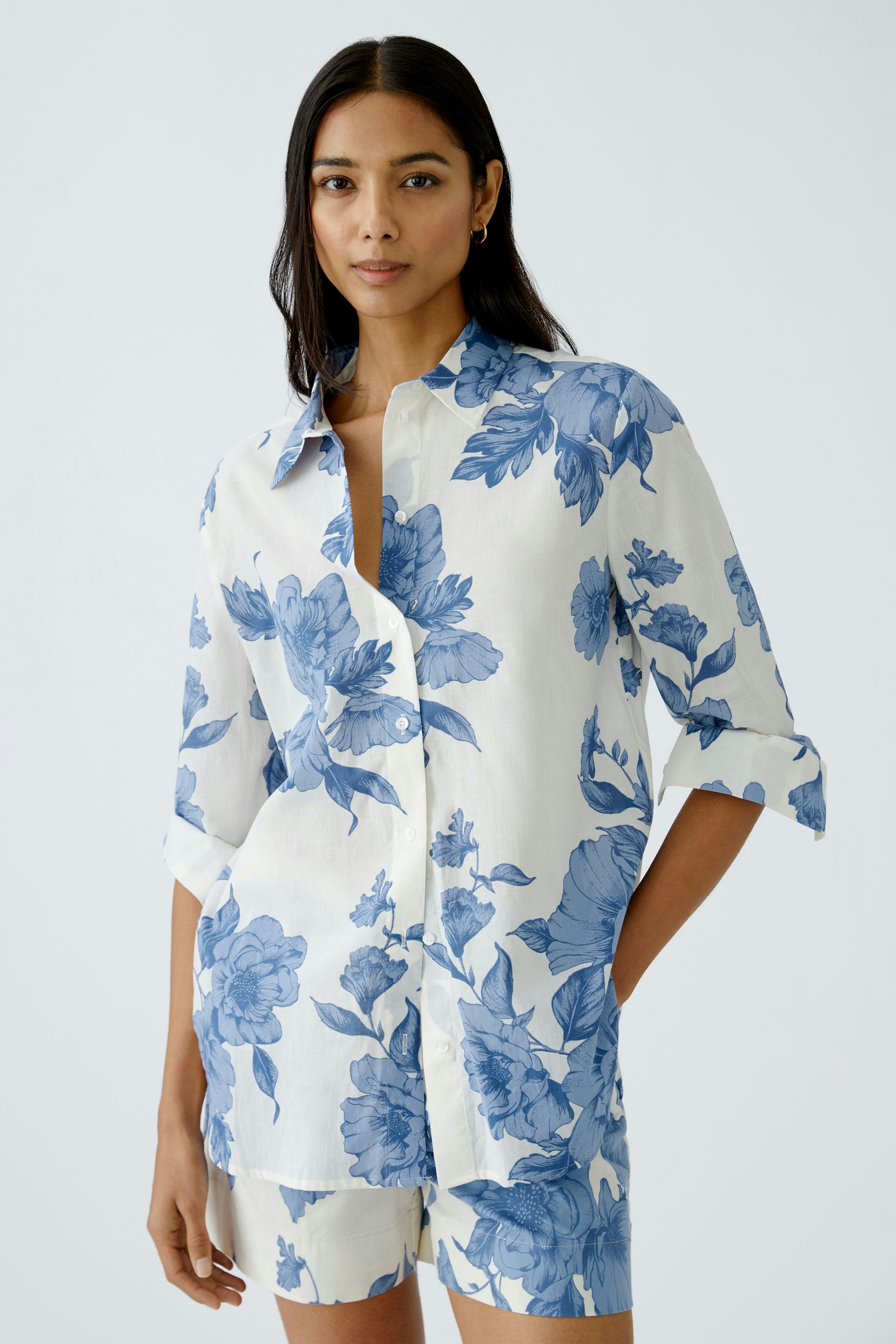 Stylish blouse: A woman in a floral button-up shirt with blue patterns, exuding elegance.