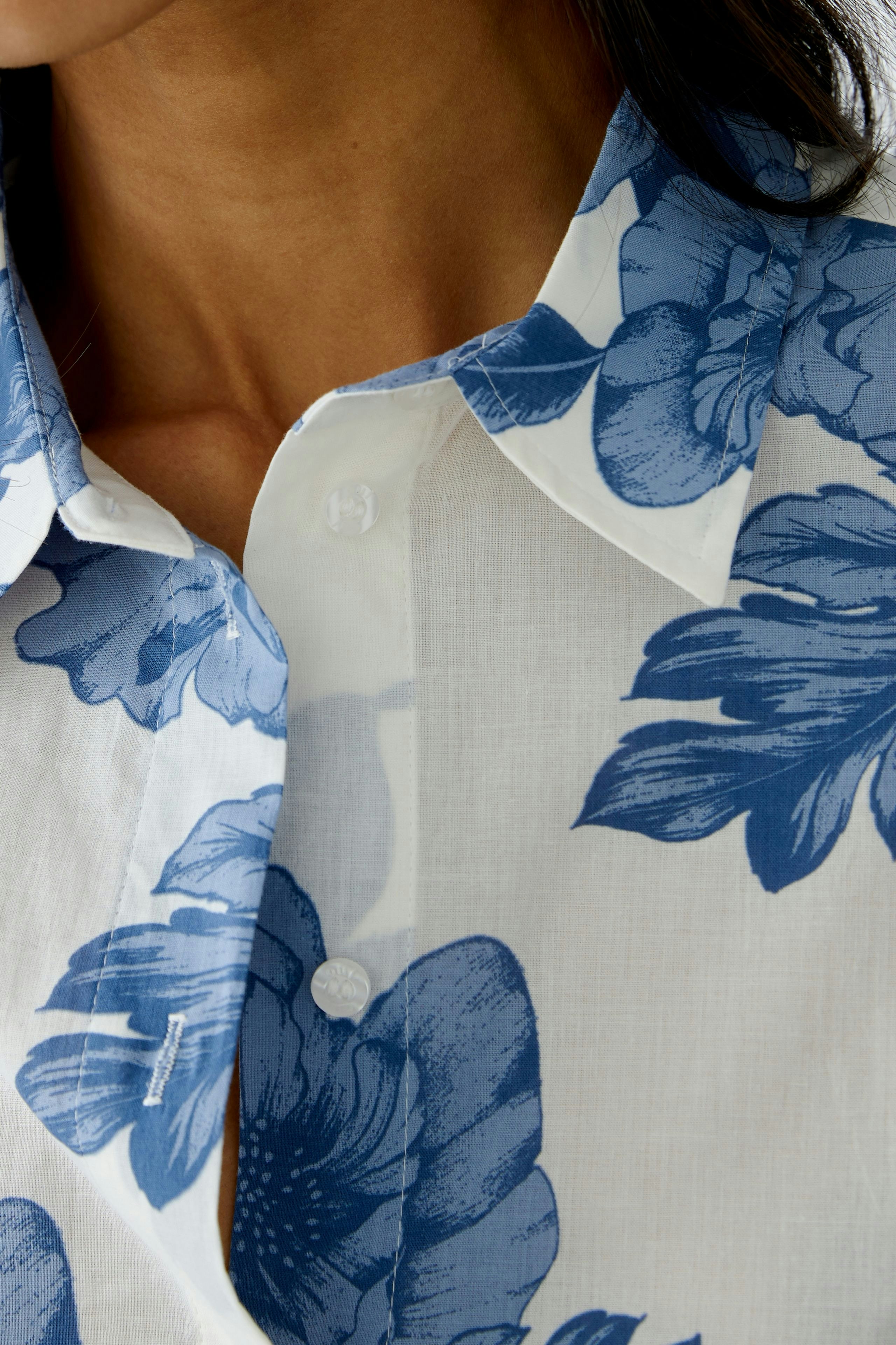 Stylish women's blouse with blue floral pattern, featuring a classic collar and button closure.