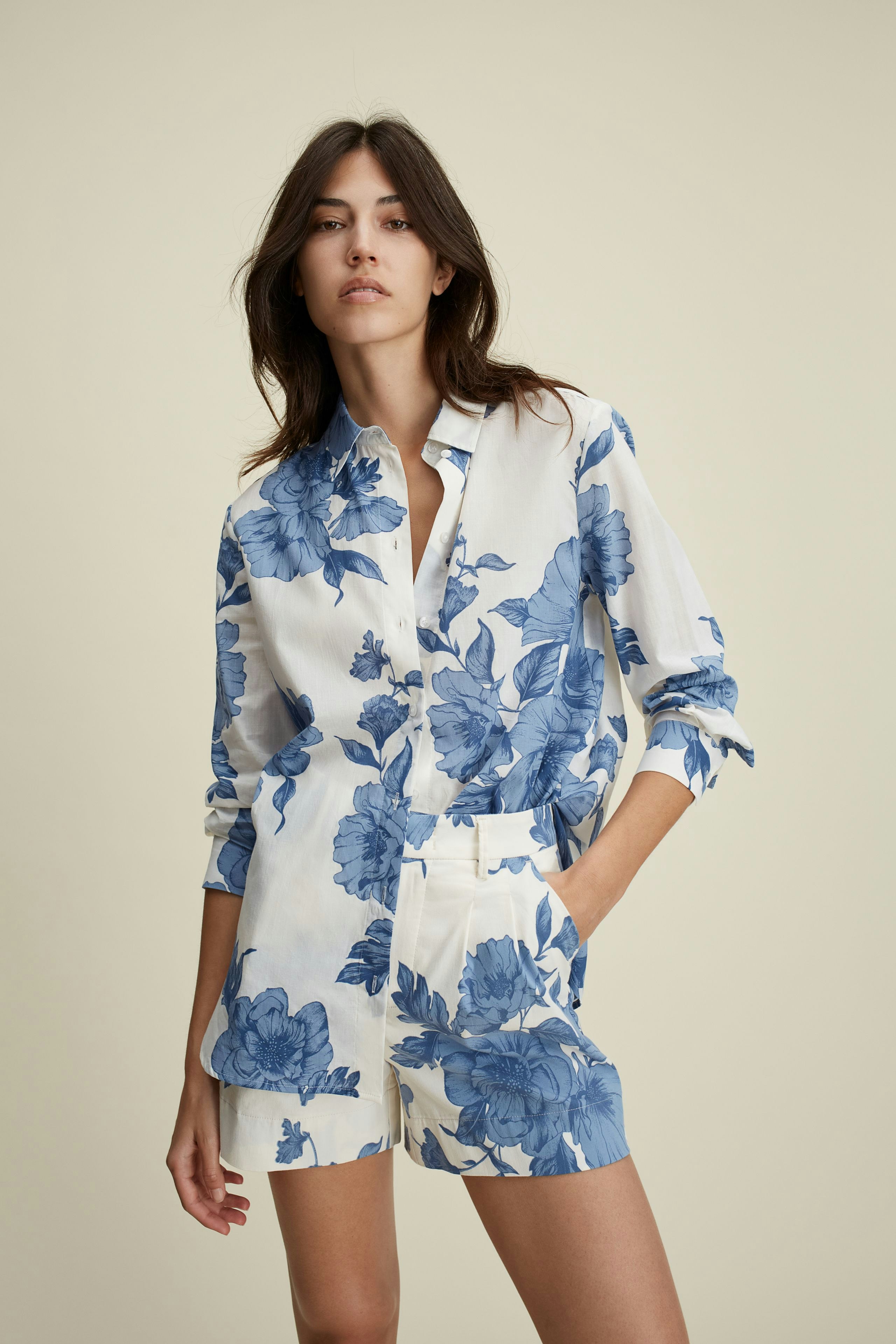 Stylish blouse: Woman in a floral-patterned blouse with blue flowers, paired with light shorts.