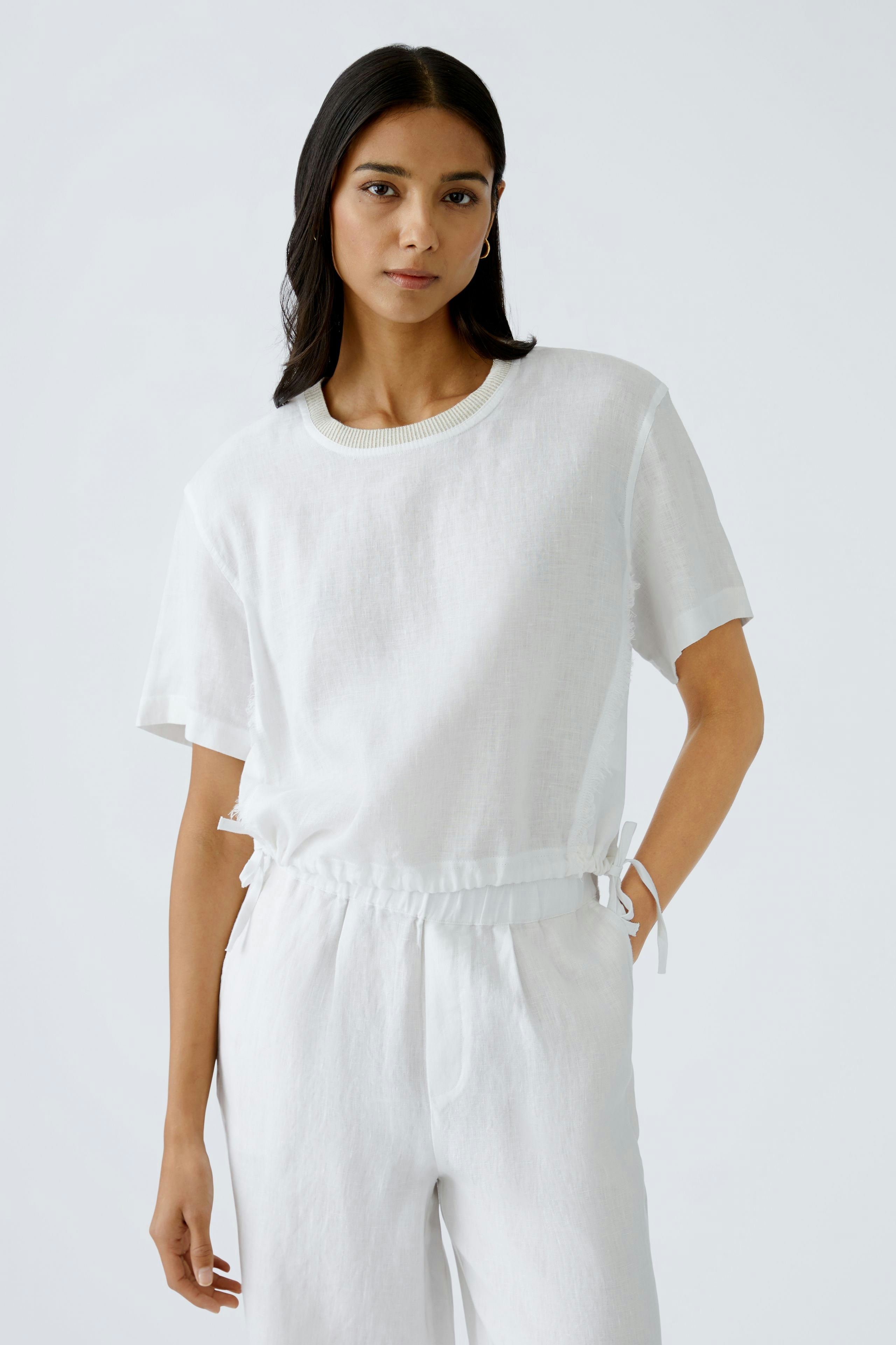Luftiges Blusenshirt: Frau in weißem, lässigem Shirt mit Rundhalsausschnitt und lockerer Passform.