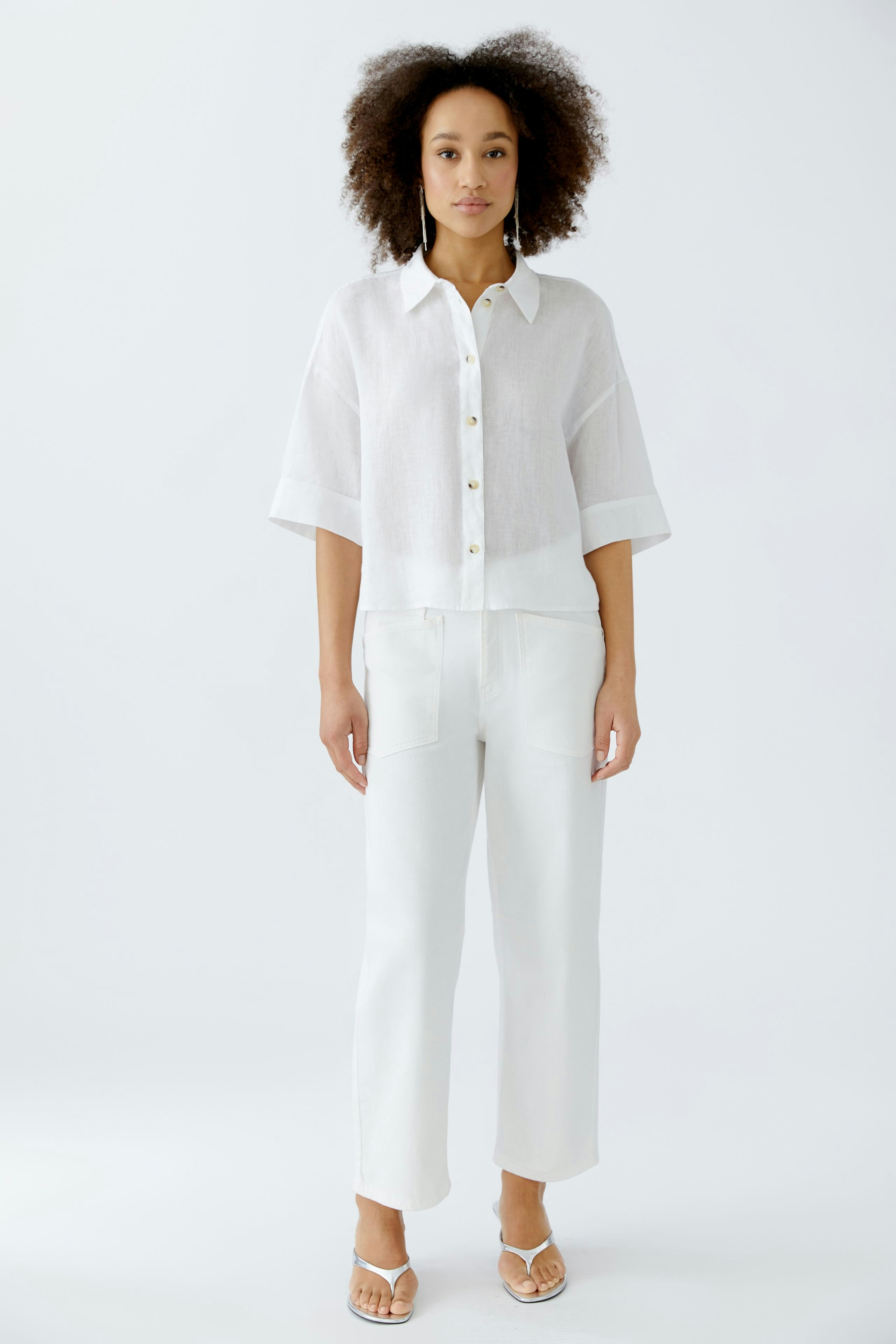 Casual women's blouse: A woman in a white button-up blouse with short sleeves and relaxed fit.