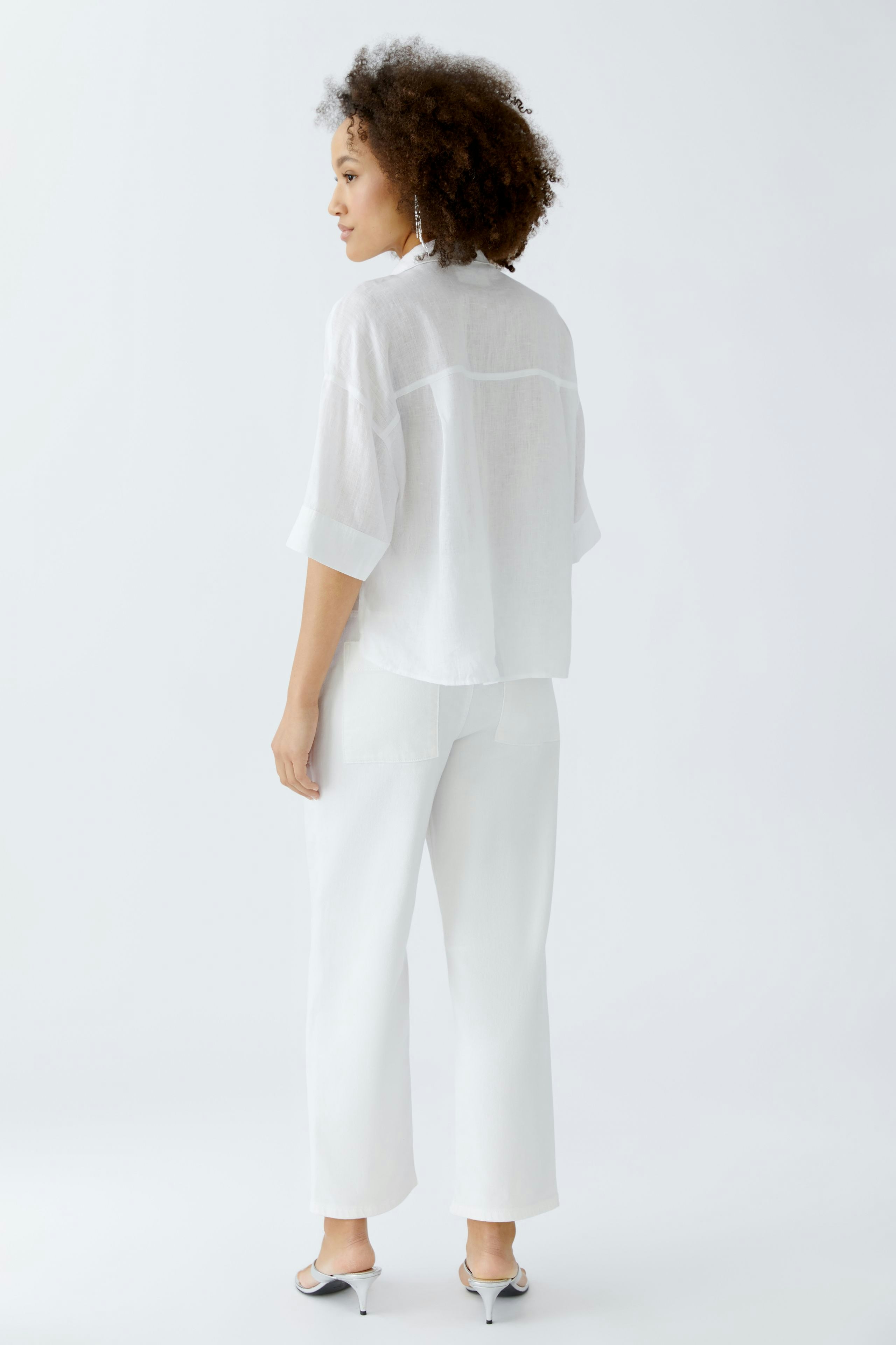 Casual women's blouse: Woman in a loose white blouse paired with wide-leg pants.