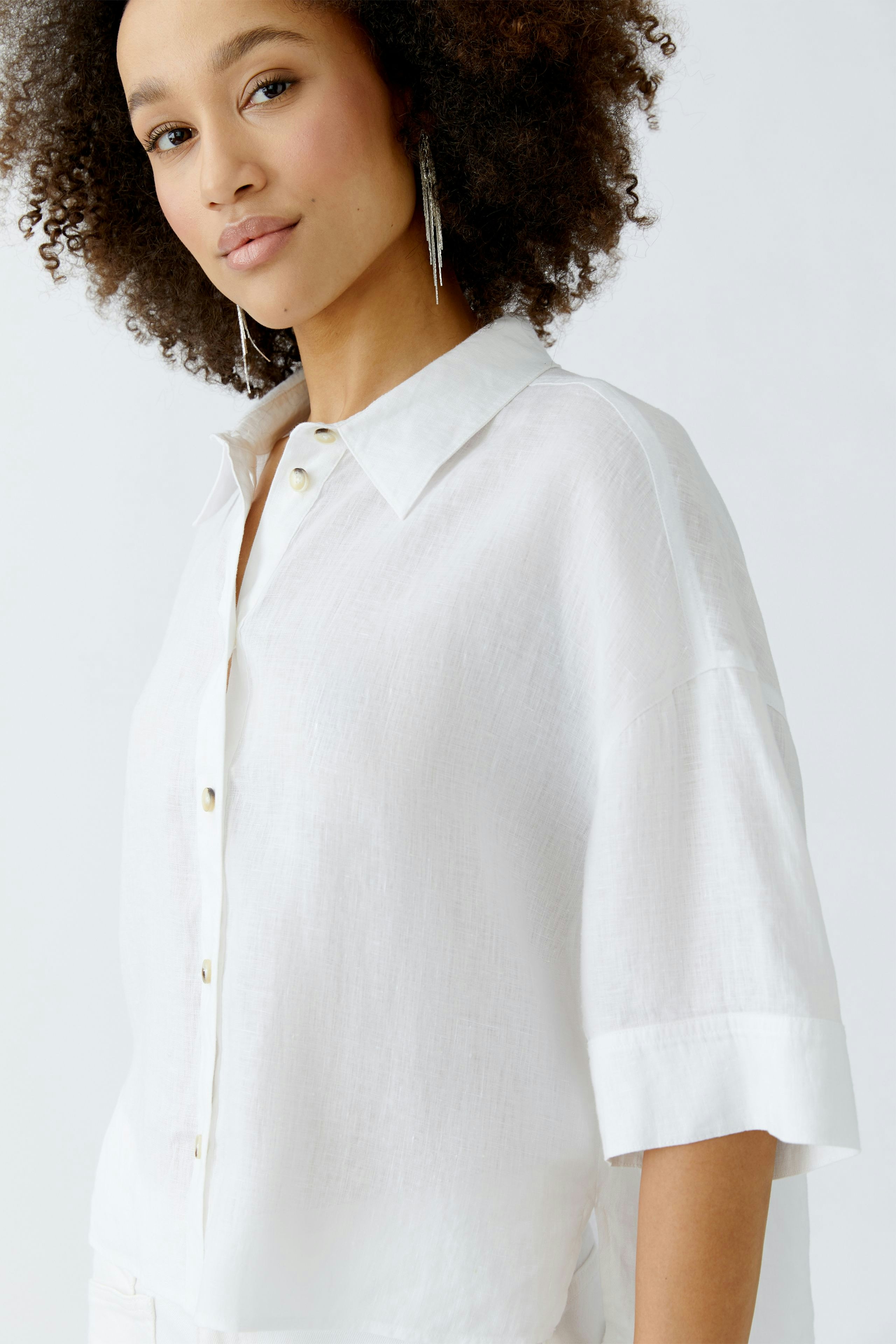 Casual women's blouse: A woman in a white, short-sleeved blouse with a relaxed fit and button details.