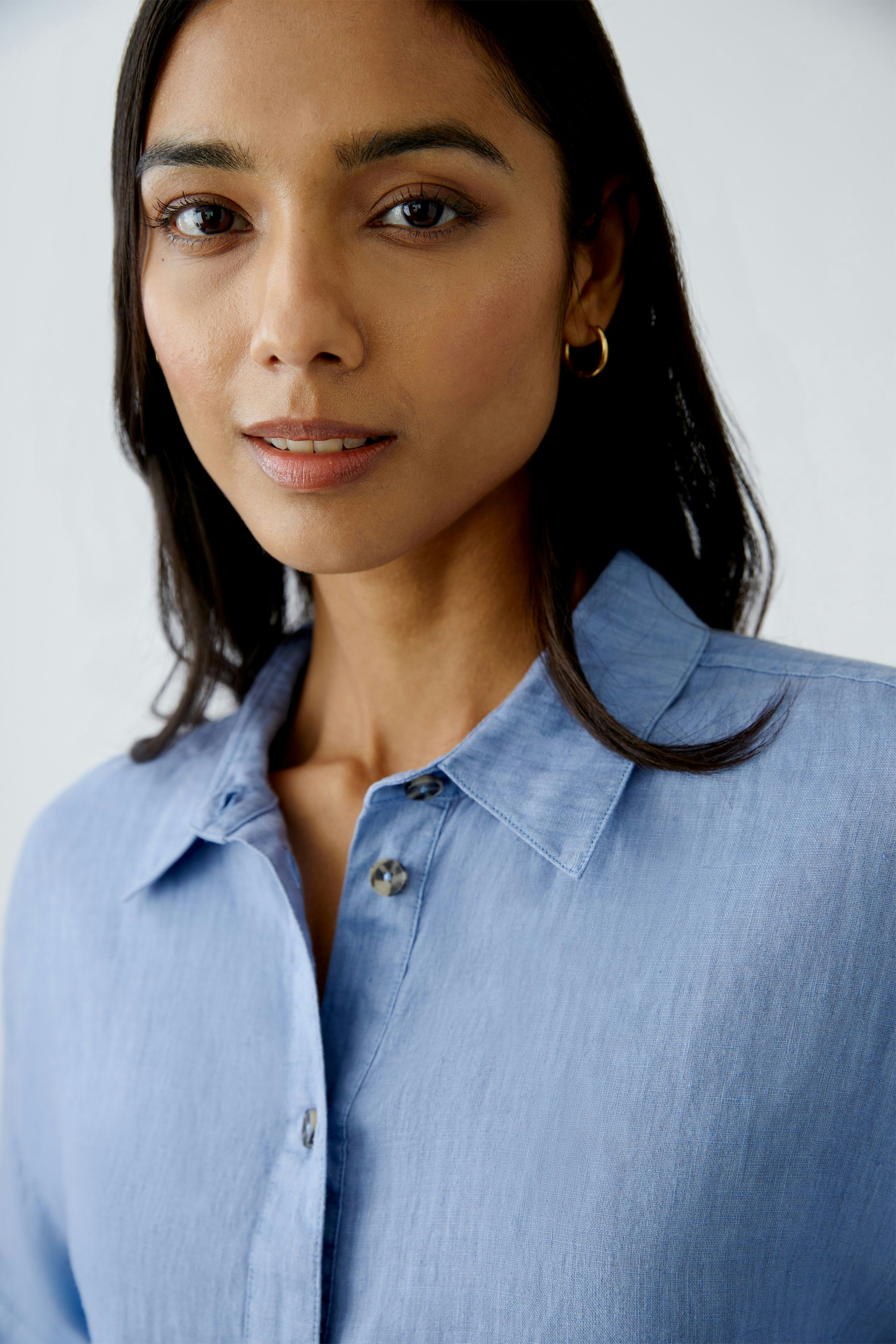 Elegante Damen-Bluse: Frau trägt eine hellblaue Bluse mit Knopfleiste und klassischem Kragen.