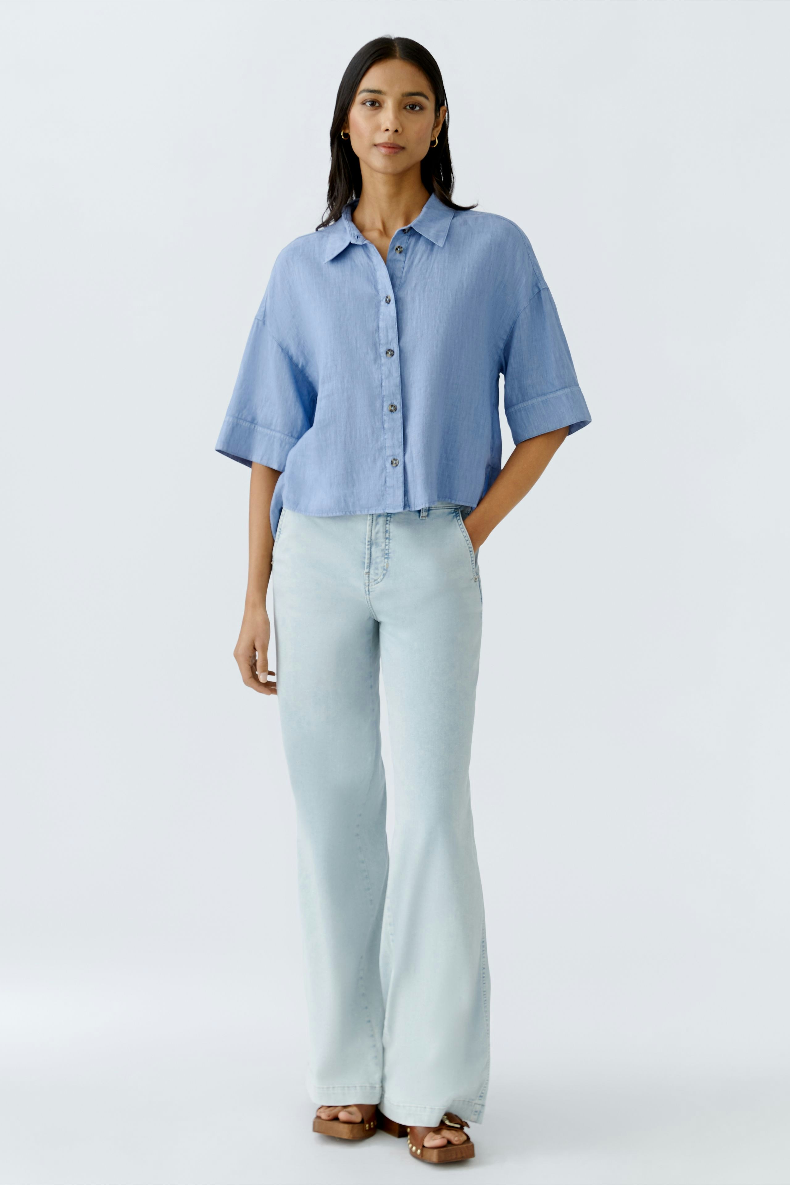 Luftige Damen-Bluse in Hellblau, lässig kombiniert mit hellen Jeans und offenen Schuhen.