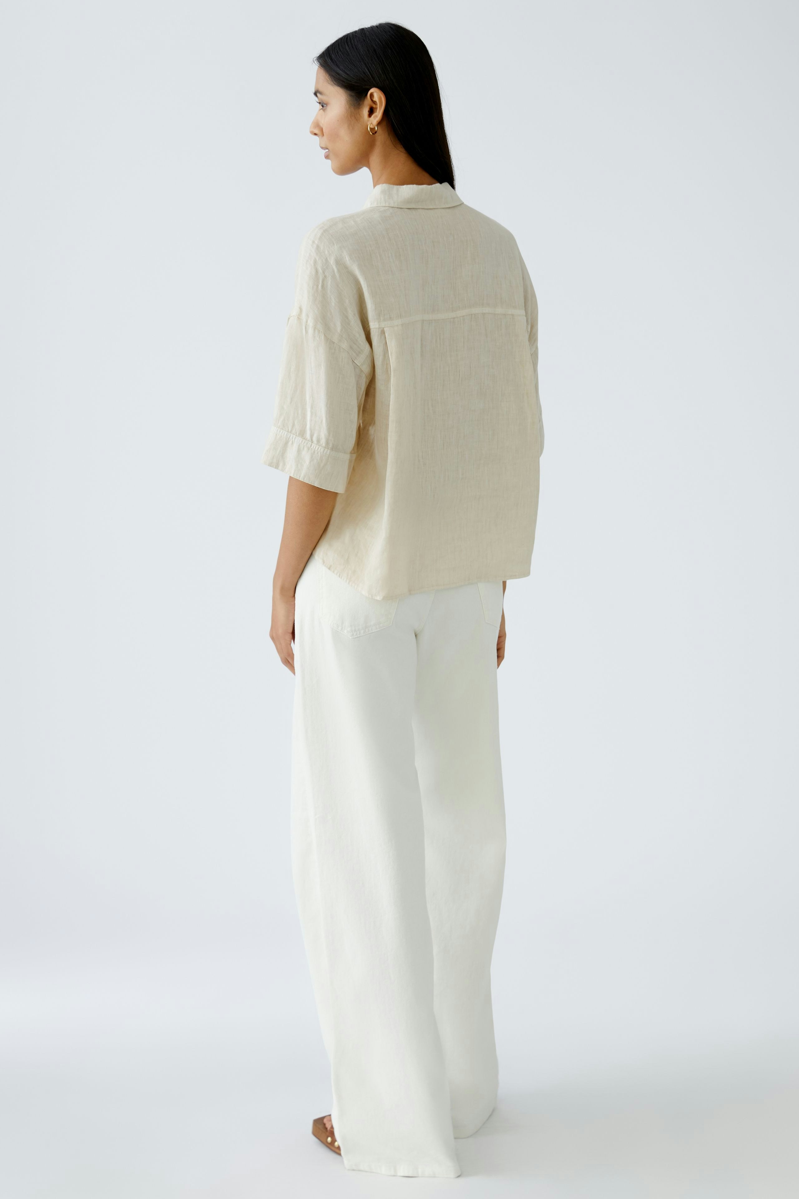 Stylish women's blouse: A woman in a light beige blouse paired with wide white pants.