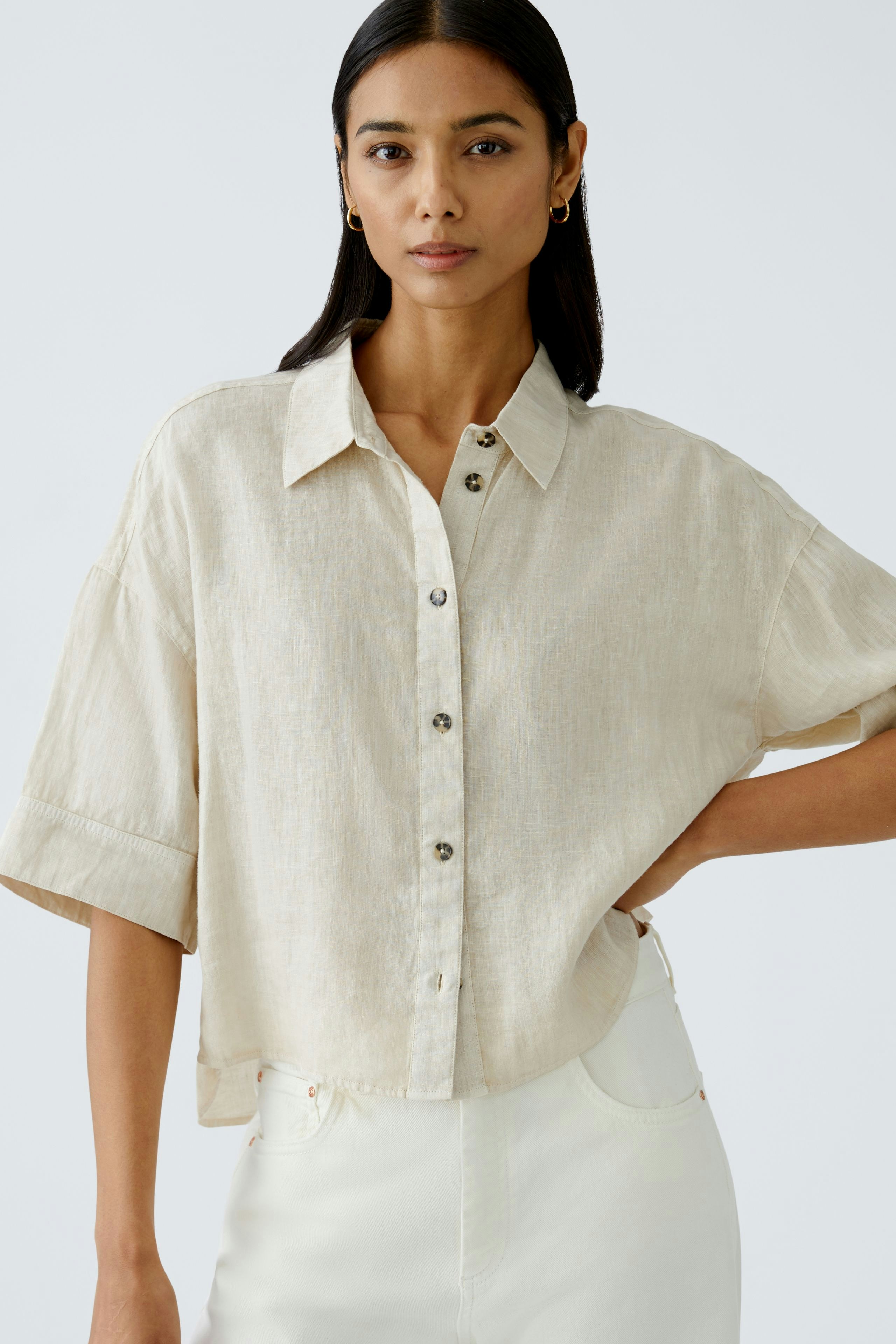 Stylish women's blouse: A woman in a light beige button-up blouse with short sleeves.