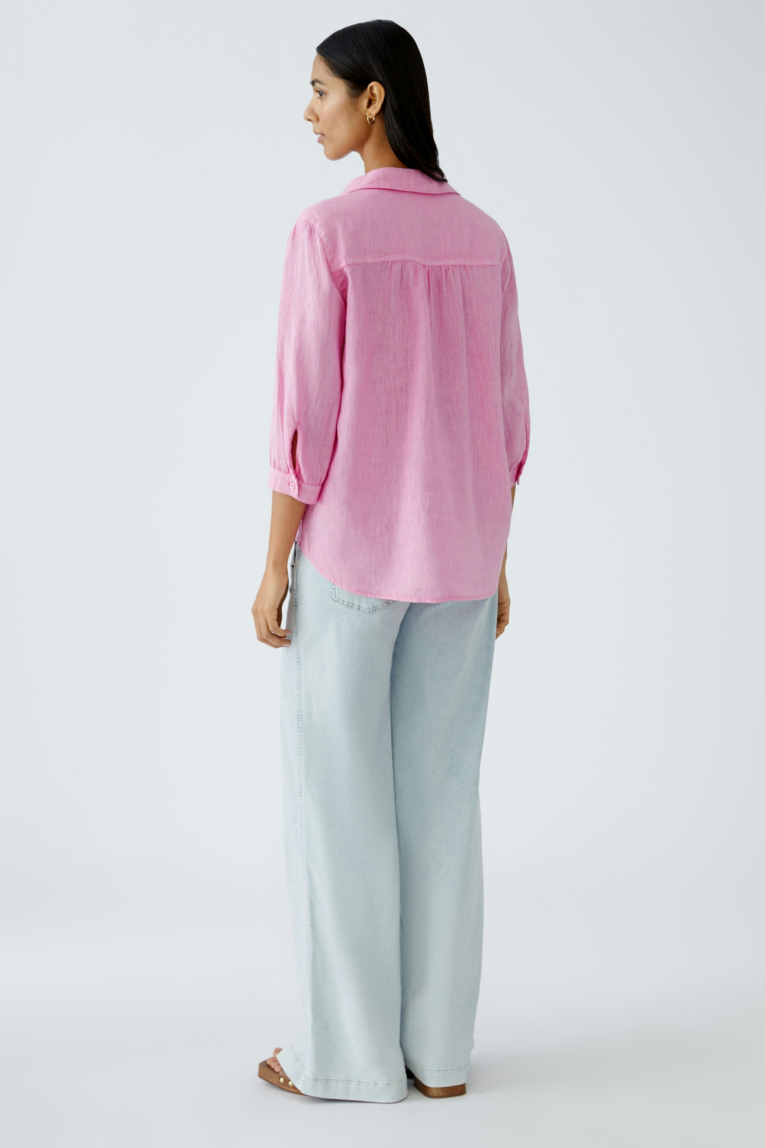 Stylish tunic: Woman in a pink tunic with three-quarter sleeves, paired with light blue wide-leg pants.