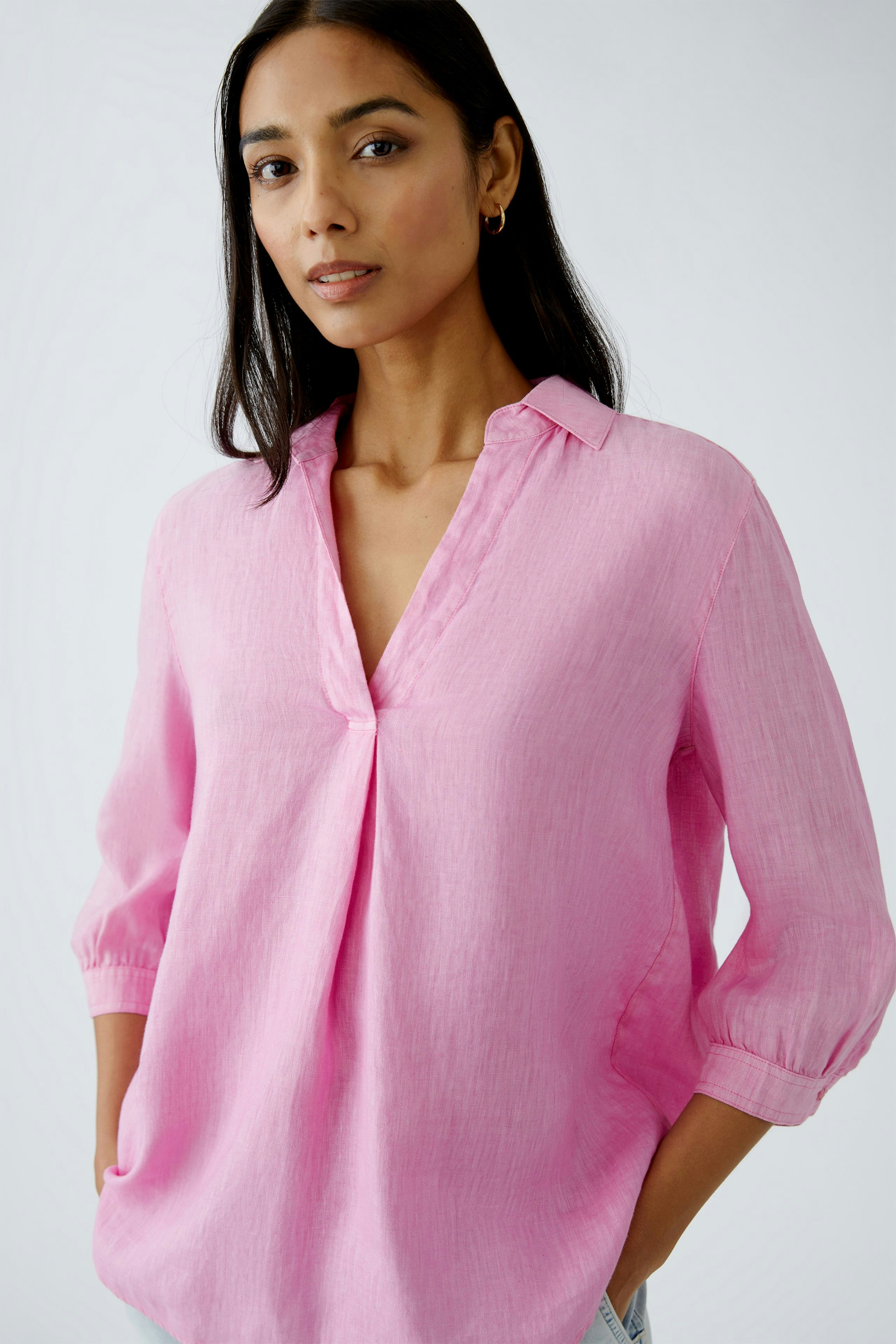 Stylish tunic: Woman in a pink tunic with a relaxed fit and a subtle collar.