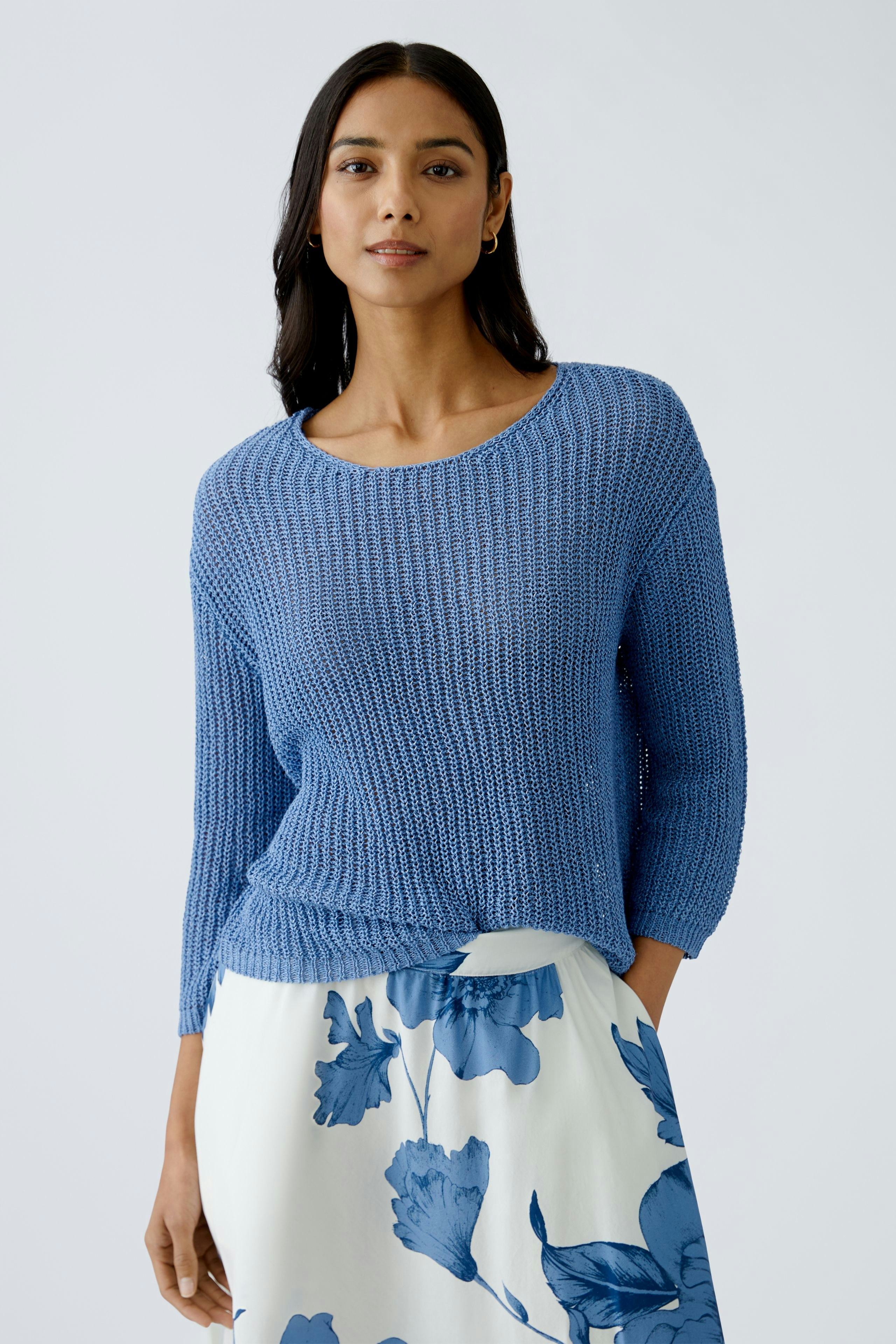 Stylish women's pullover: A woman in a blue knitted pullover paired with a floral skirt.
