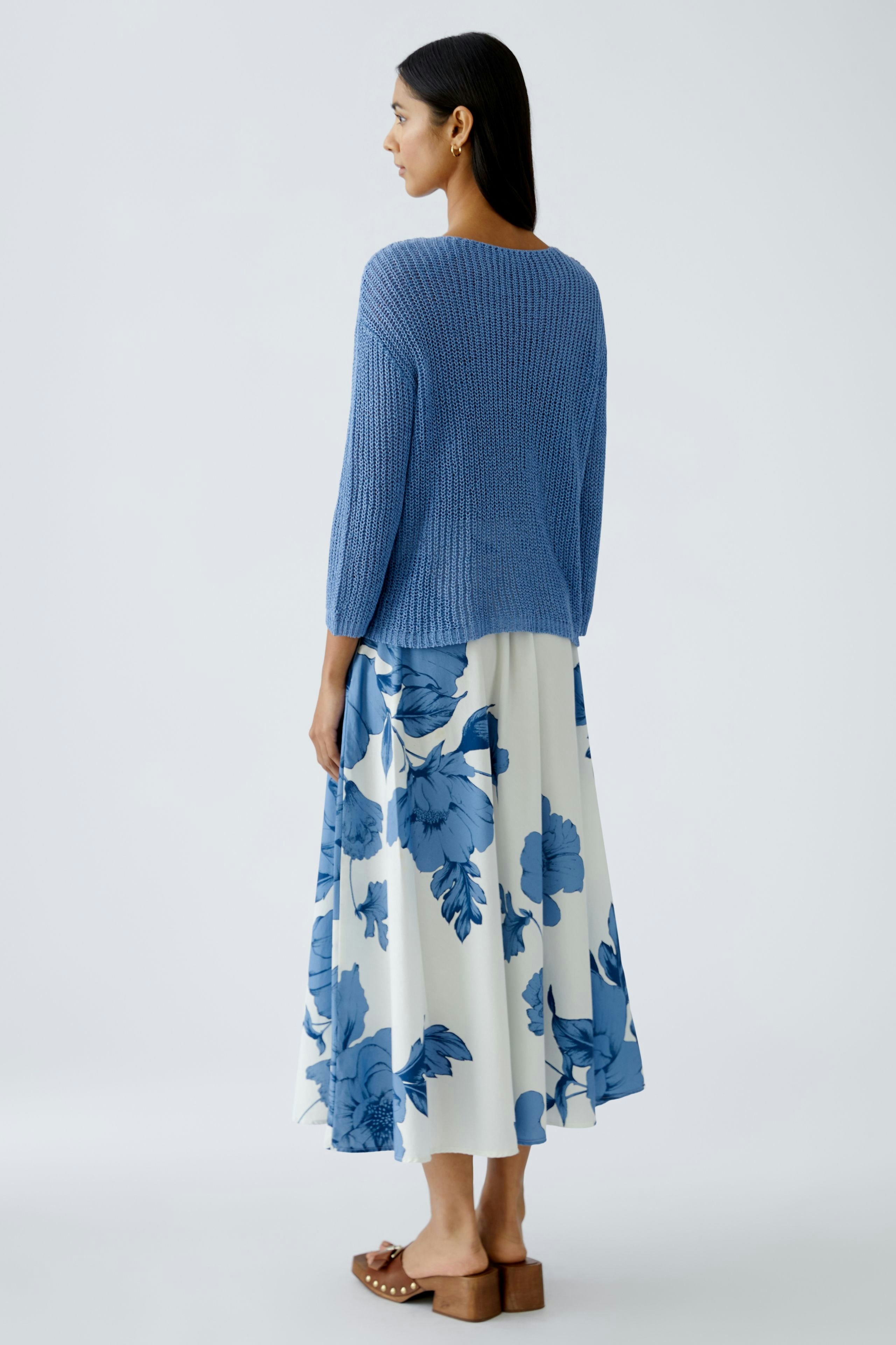 Stylish women's pullover: A woman in a blue knitted pullover paired with a floral skirt.