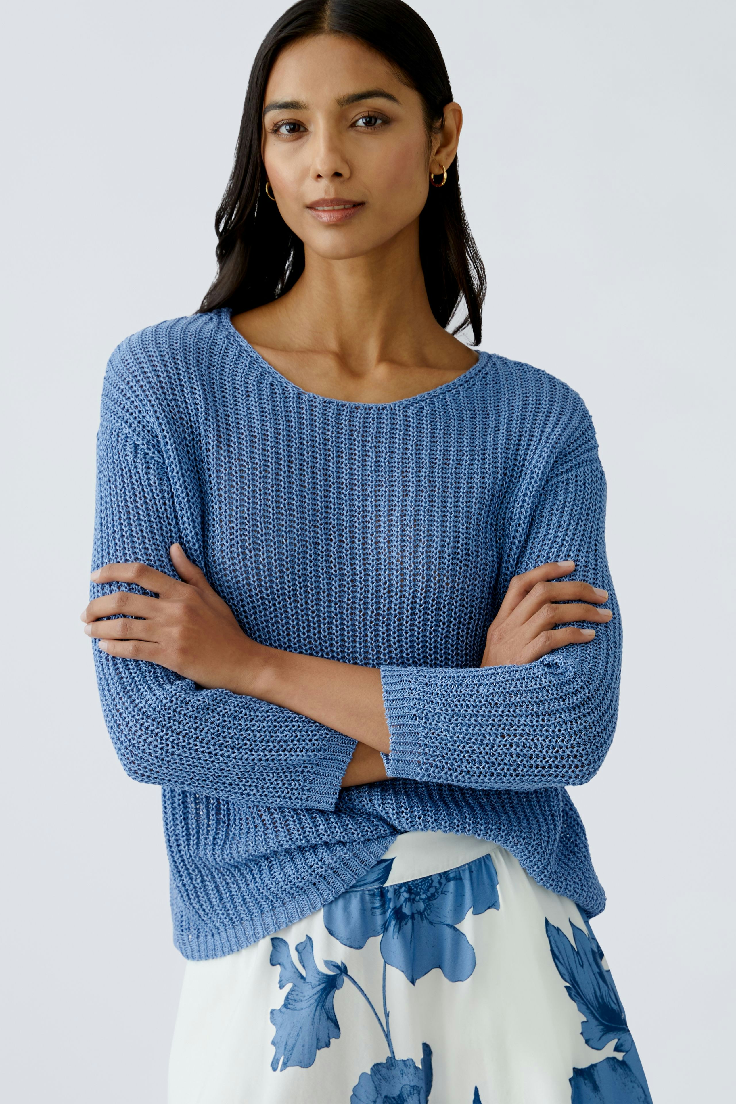 Modern women's pullover: A woman in a blue knitted pullover, paired with a floral skirt.