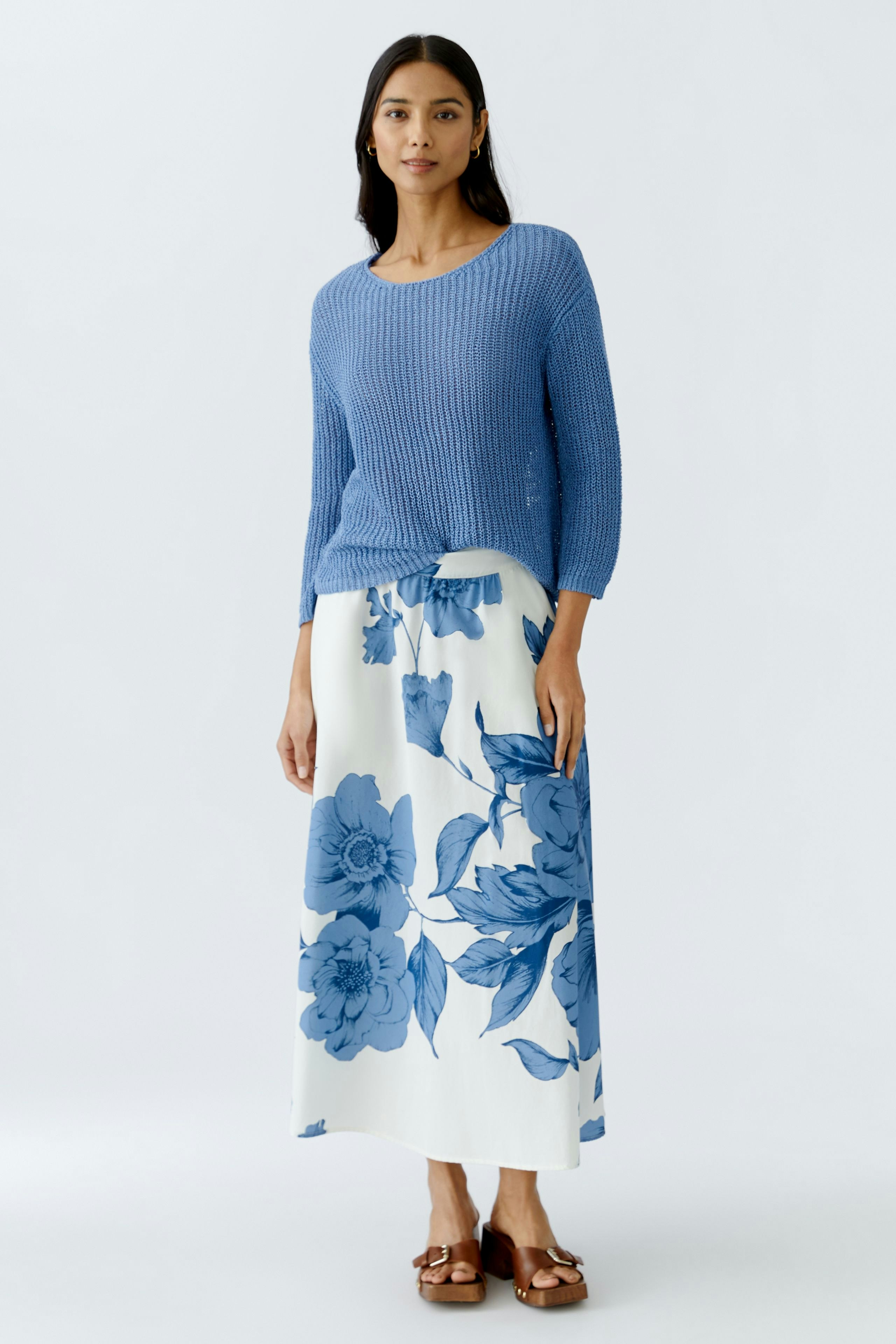 Stylish women's pullover: A woman in a blue knitted pullover paired with a floral skirt.