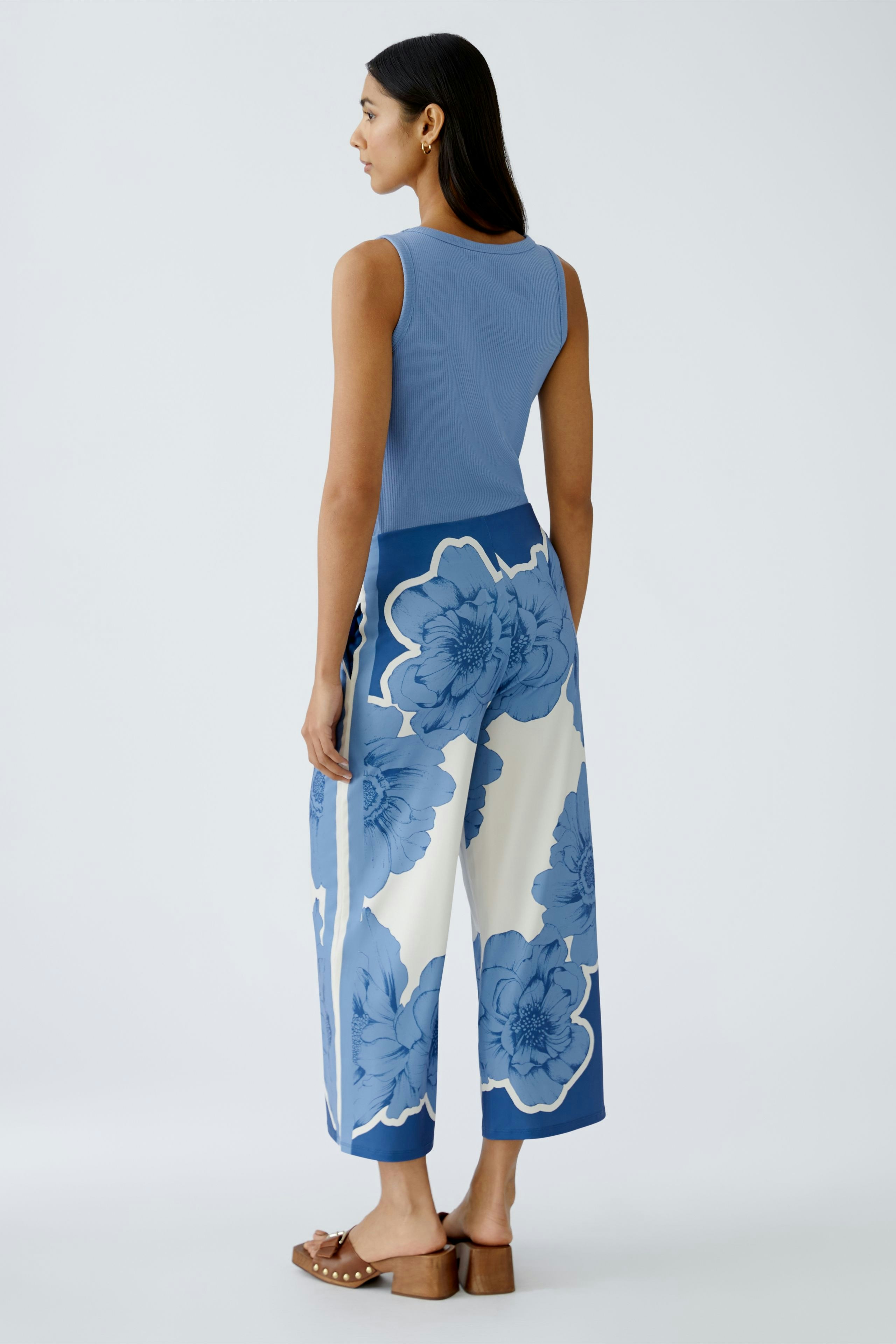 Stylish women's trousers: A woman in blue floral wide-leg trousers, showcasing a modern and elegant look.