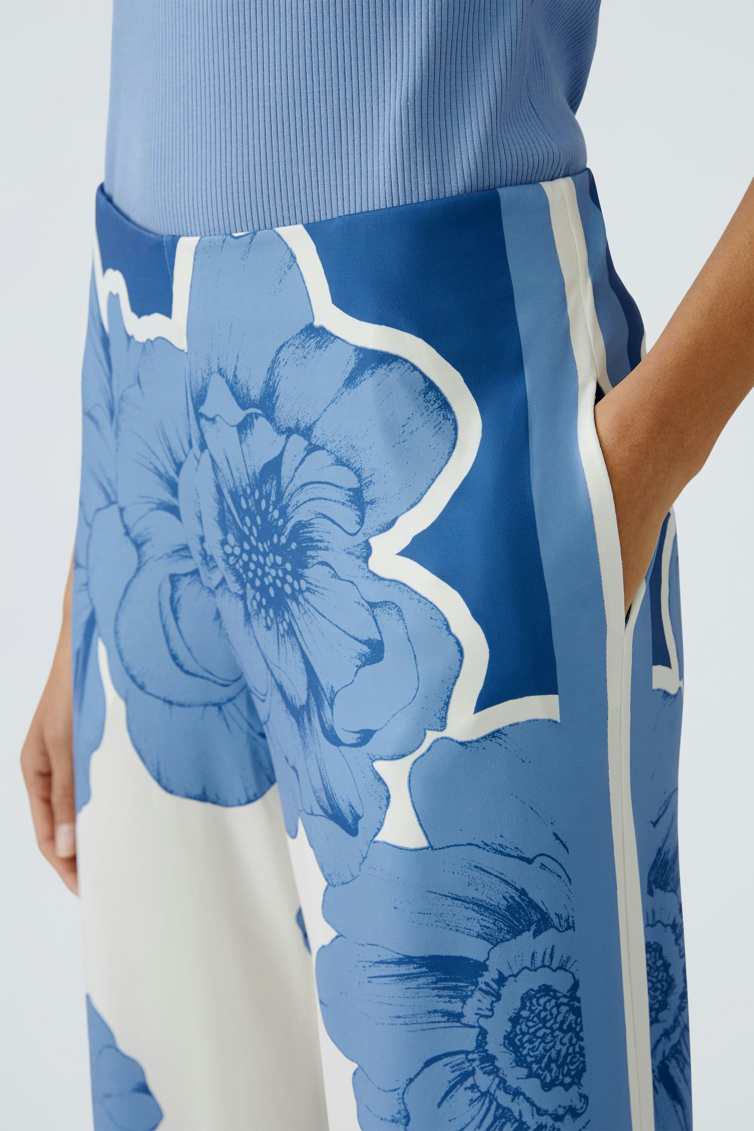 Stylish women's trousers: Close-up of a woman wearing blue floral patterned pants with pockets.