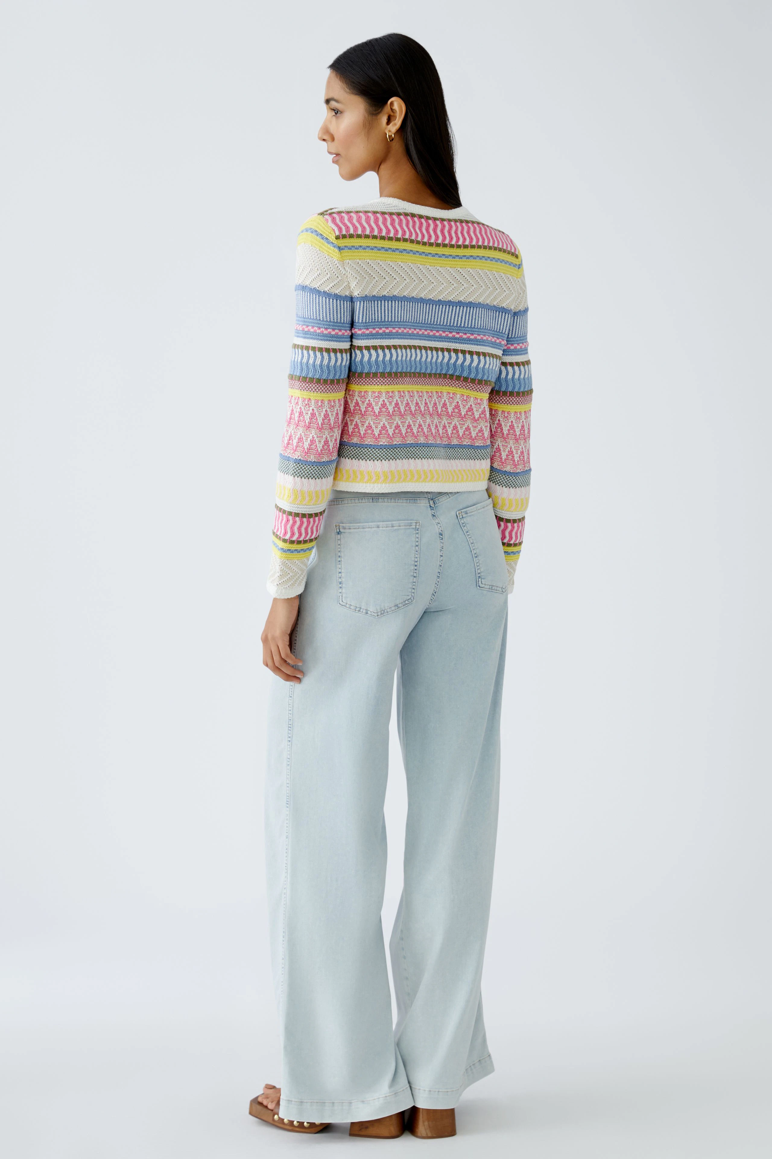 Colorful women's pullover: A woman in a vibrant striped pullover with wide-leg jeans.