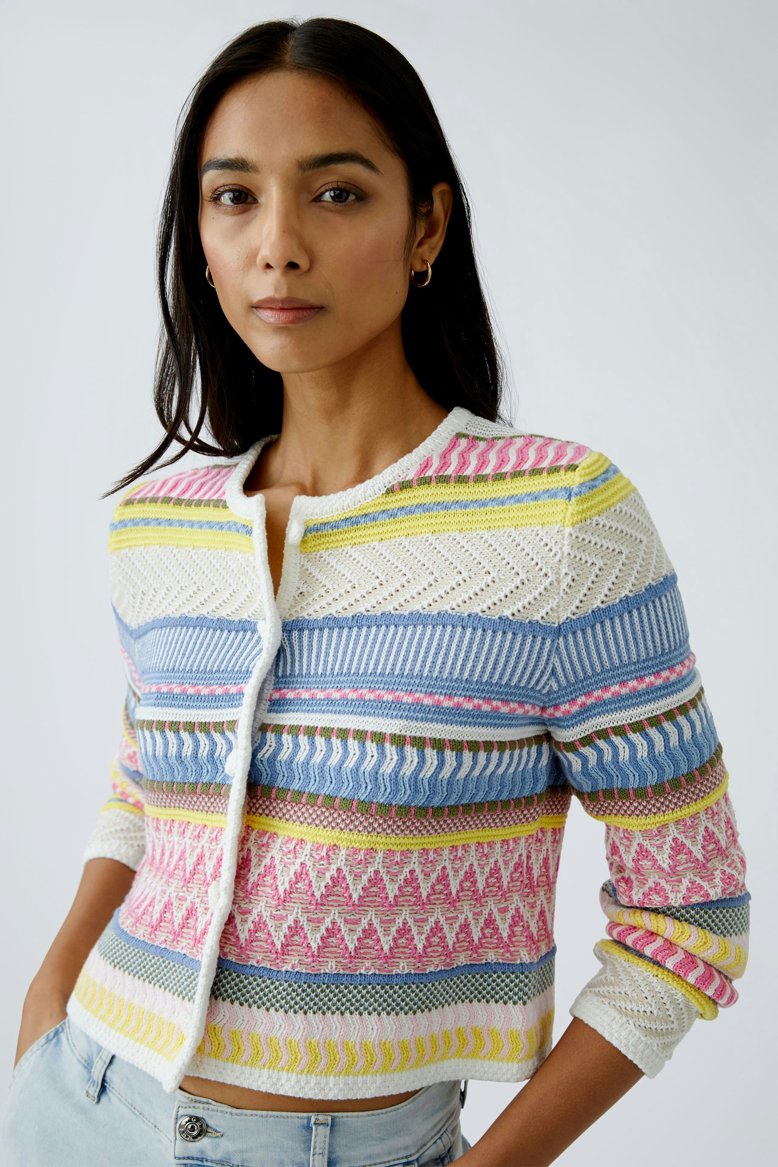Bunte Damen-Strickjacke: Frau in farbenfroher Strickjacke mit geometrischen Mustern und lässigem Look.