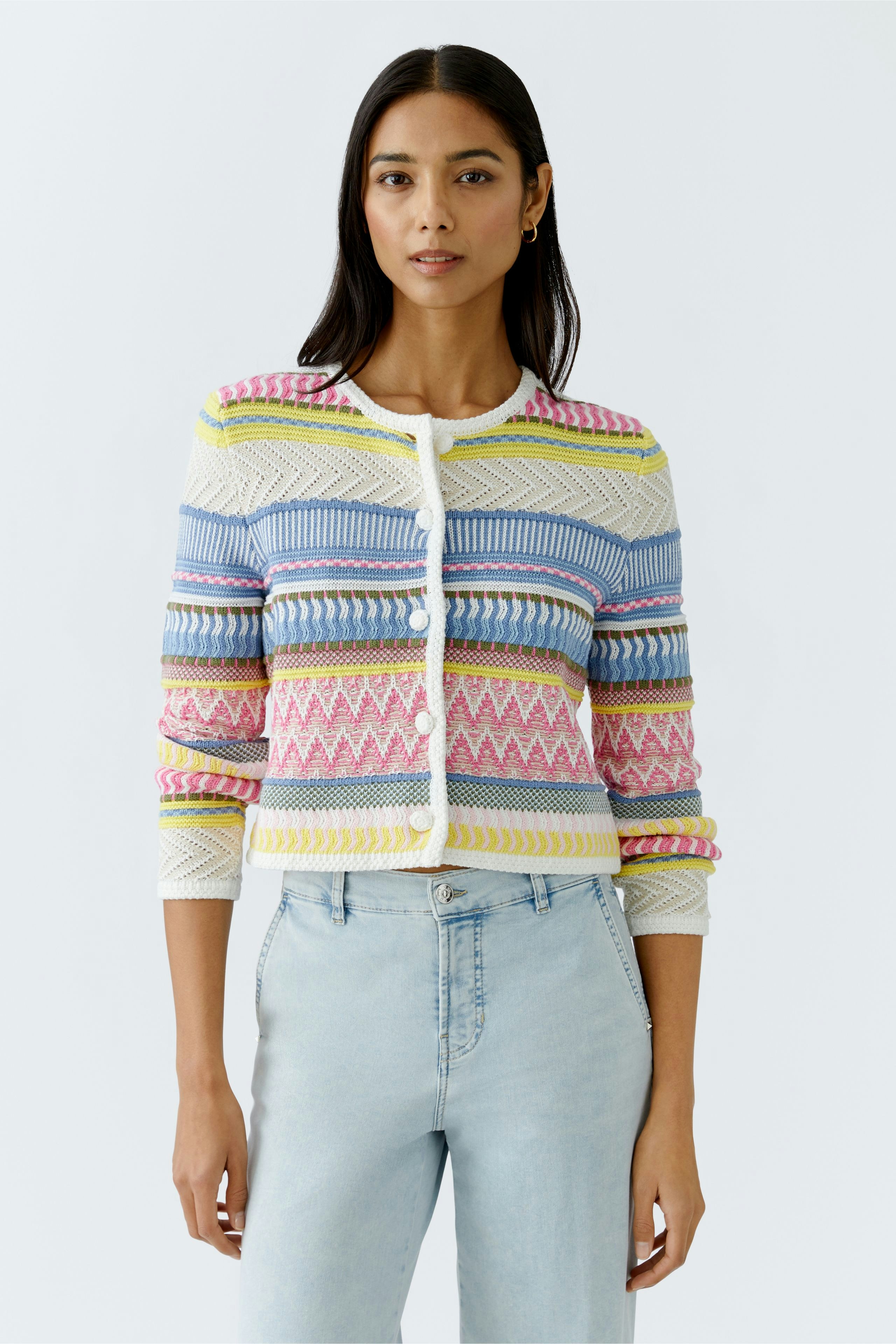 Bunte Damen-Strickjacke: Frau trägt eine farbenfrohe Strickjacke mit geometrischem Muster und Knöpfen.