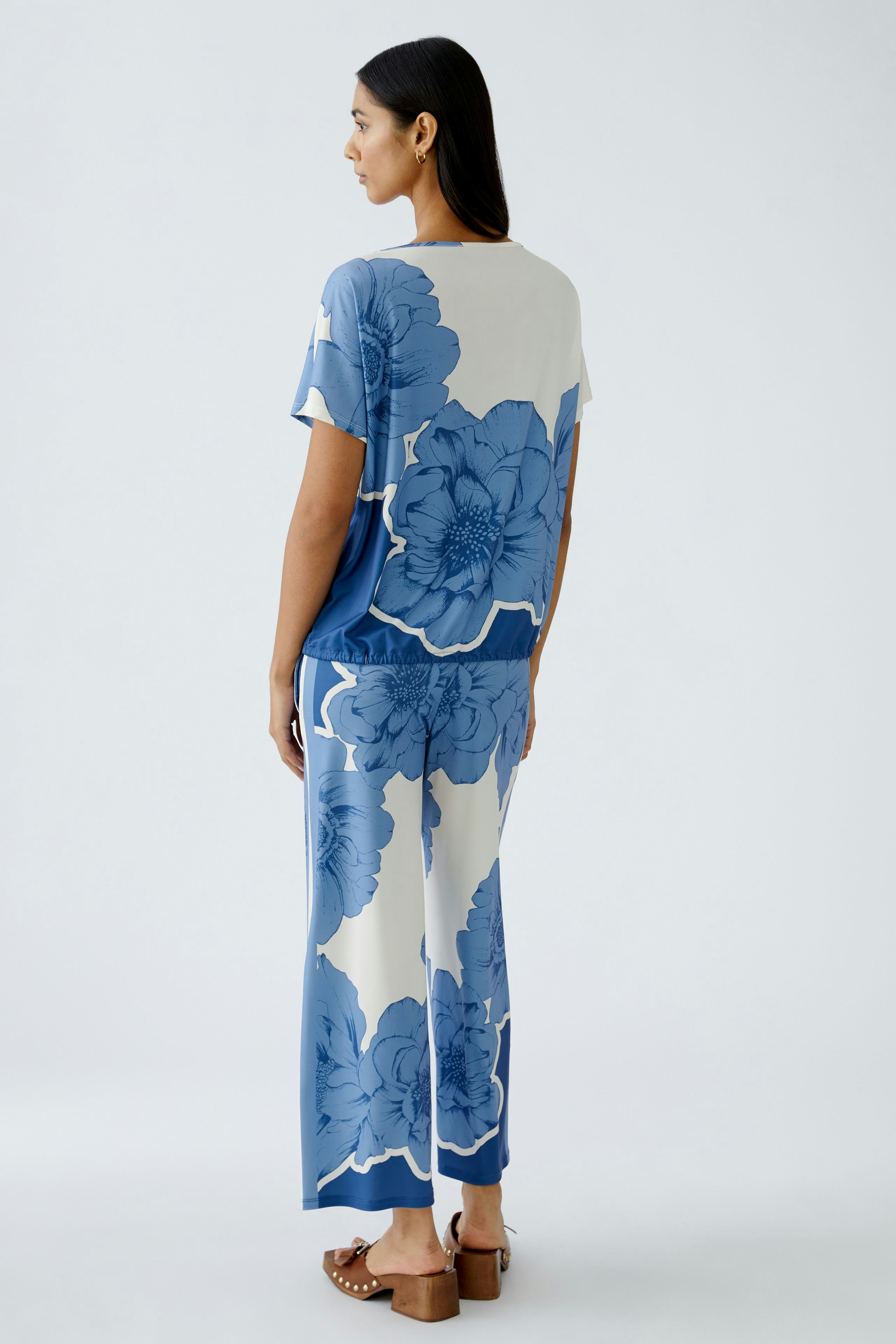 Stylish women's T-shirt: A woman in a blue floral print top, showcasing a relaxed and modern look.