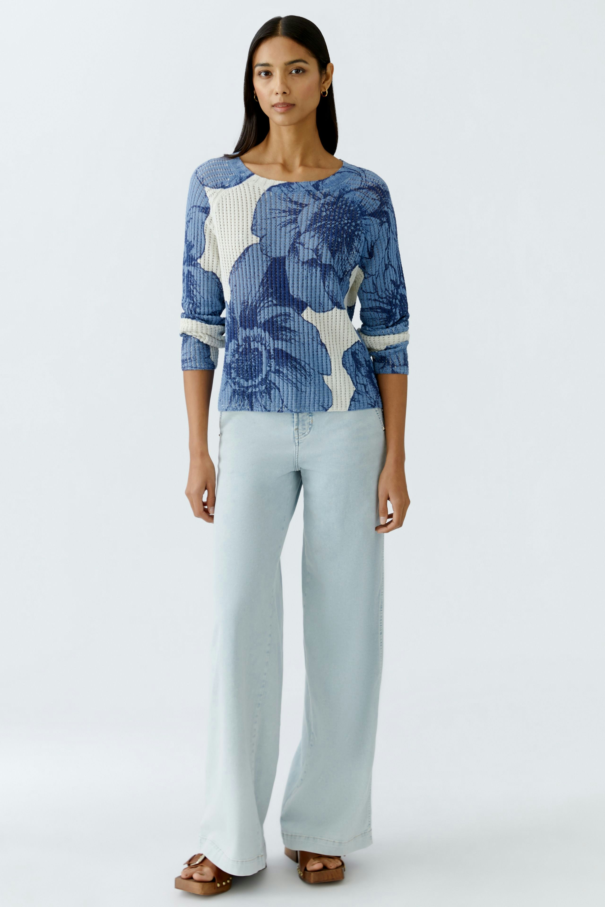 Damen-Pullover: Frau in blauem, floral gemustertem Pullover mit lässigen Jeans und Sandalen.