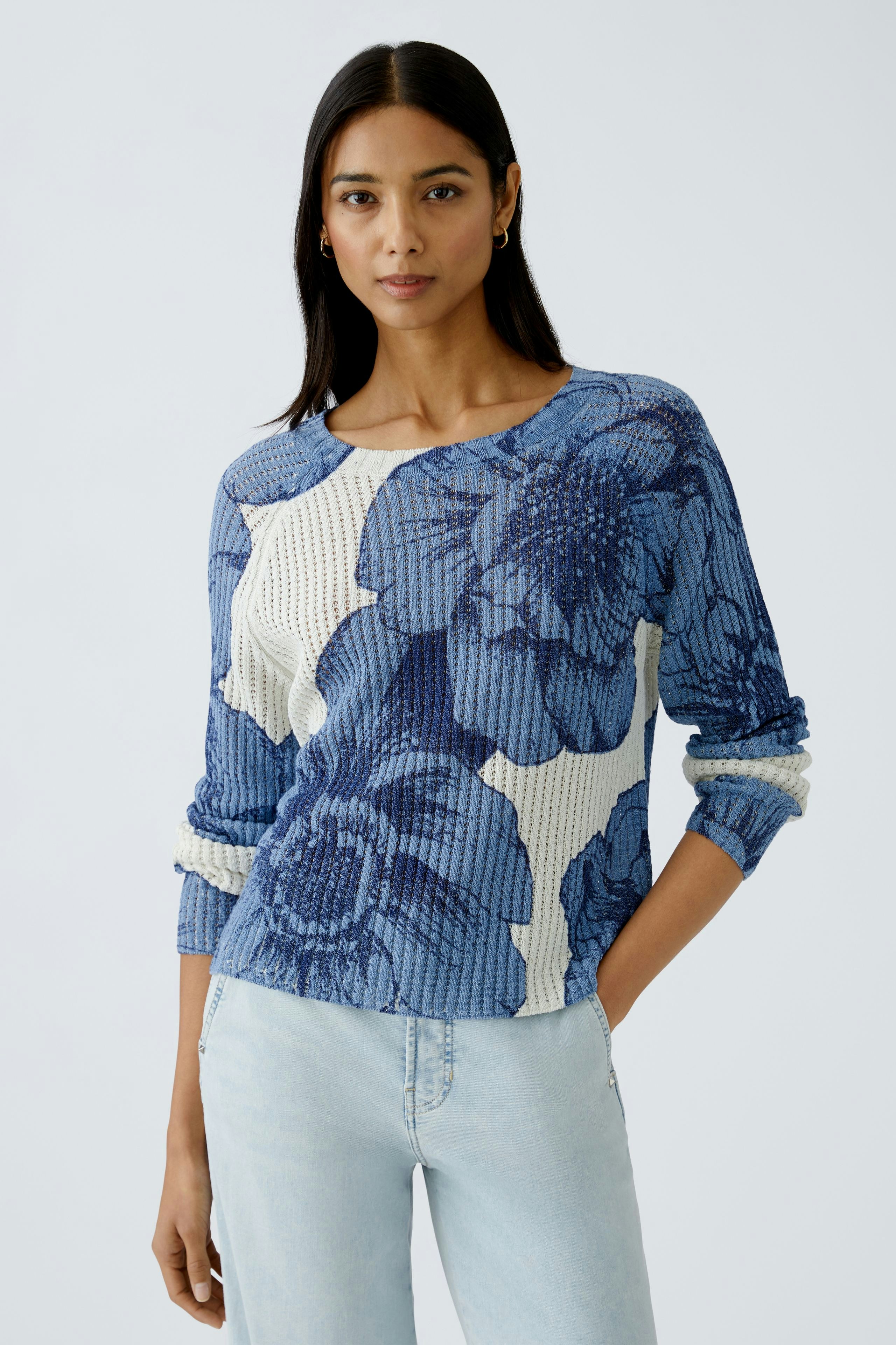Damen-Pullover: Frau in blauem, floralem Strickpullover mit lässigem Schnitt und Rundhalsausschnitt.