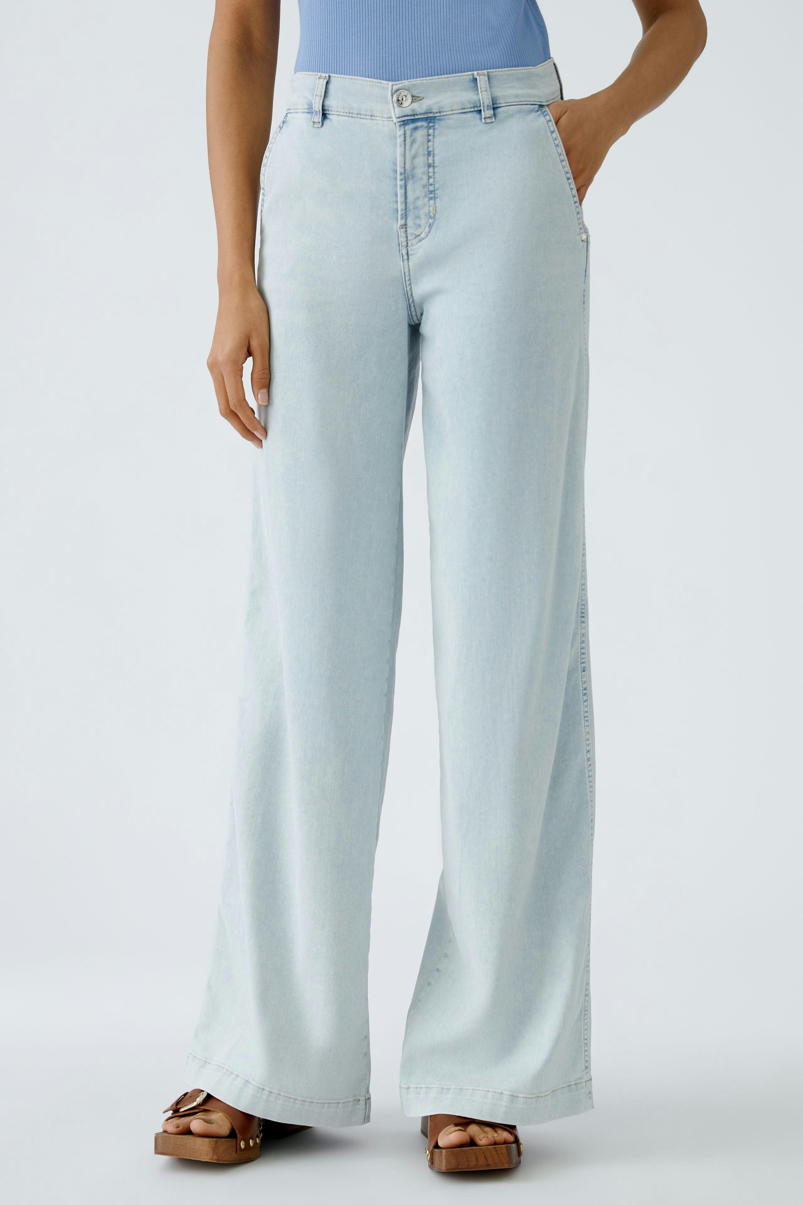 Flared Jeans: Frau trägt helle, weite Jeans mit lässigem Schnitt und modischen Sandalen.