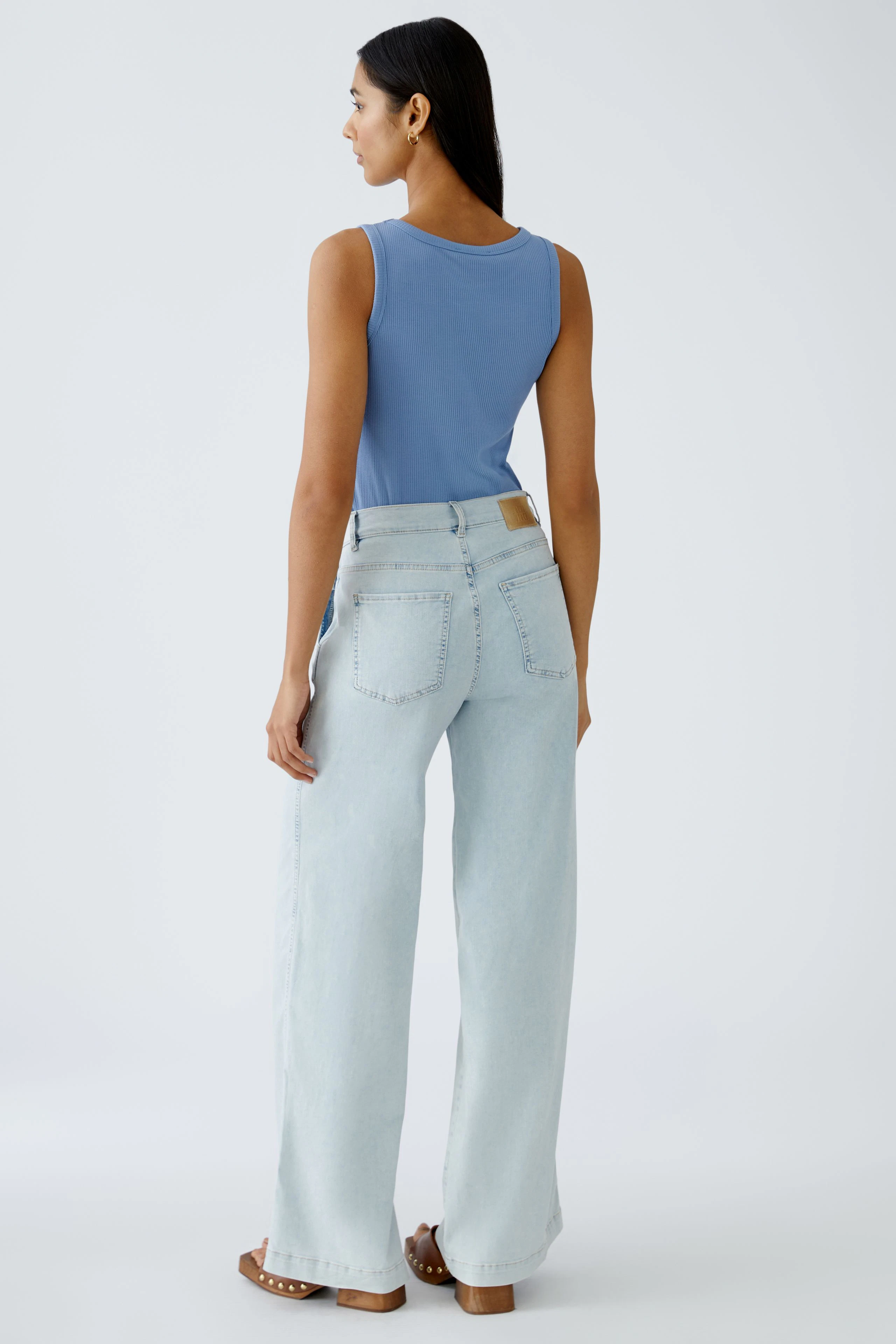Stylish flared jeans: Woman in light blue flared jeans with a relaxed fit, showcasing a modern silhouette.