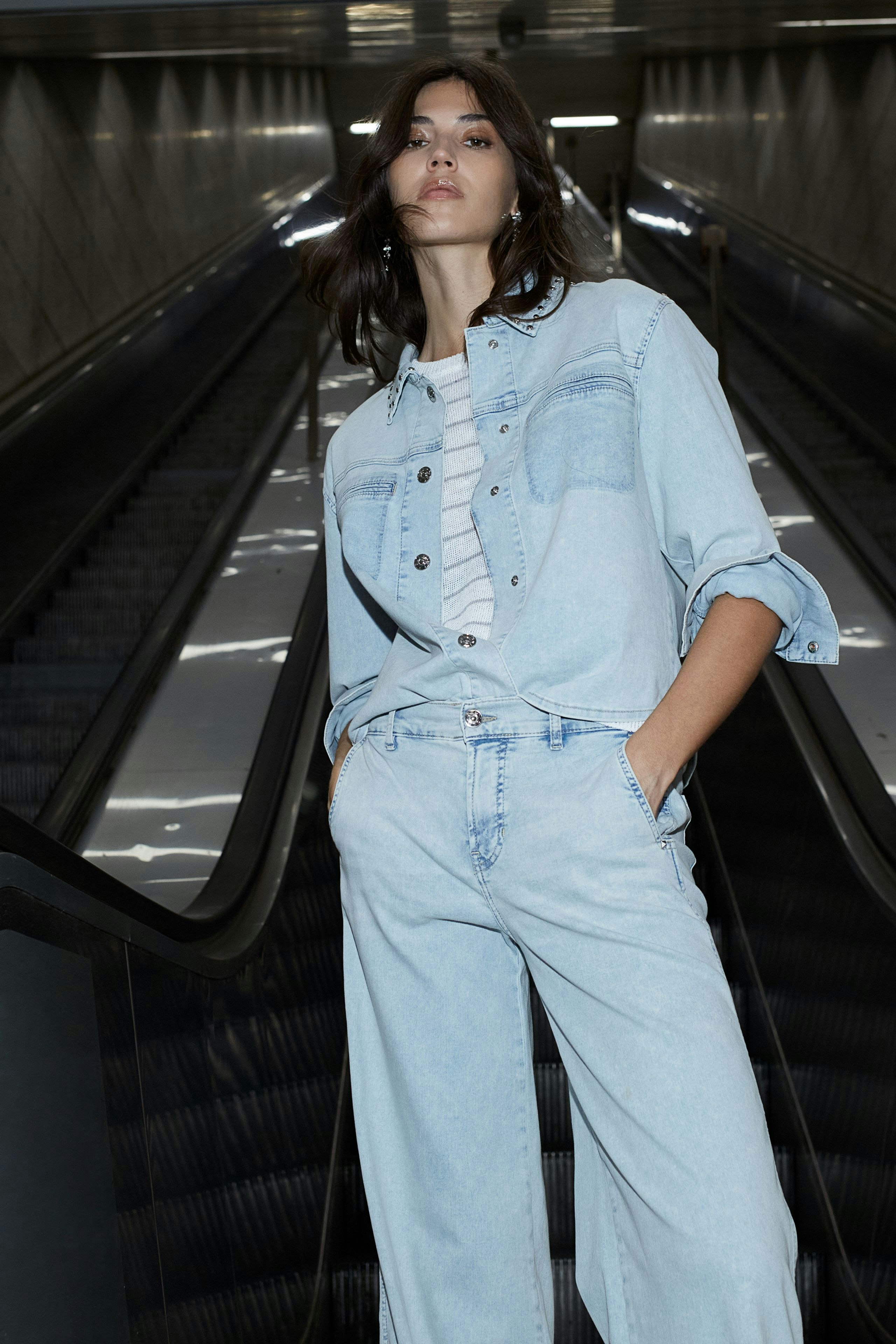 Damen Jeans Flared: Frau in lässigen, hellen Jeans mit weitem Bein und buntem, gemustertem Oberteil.