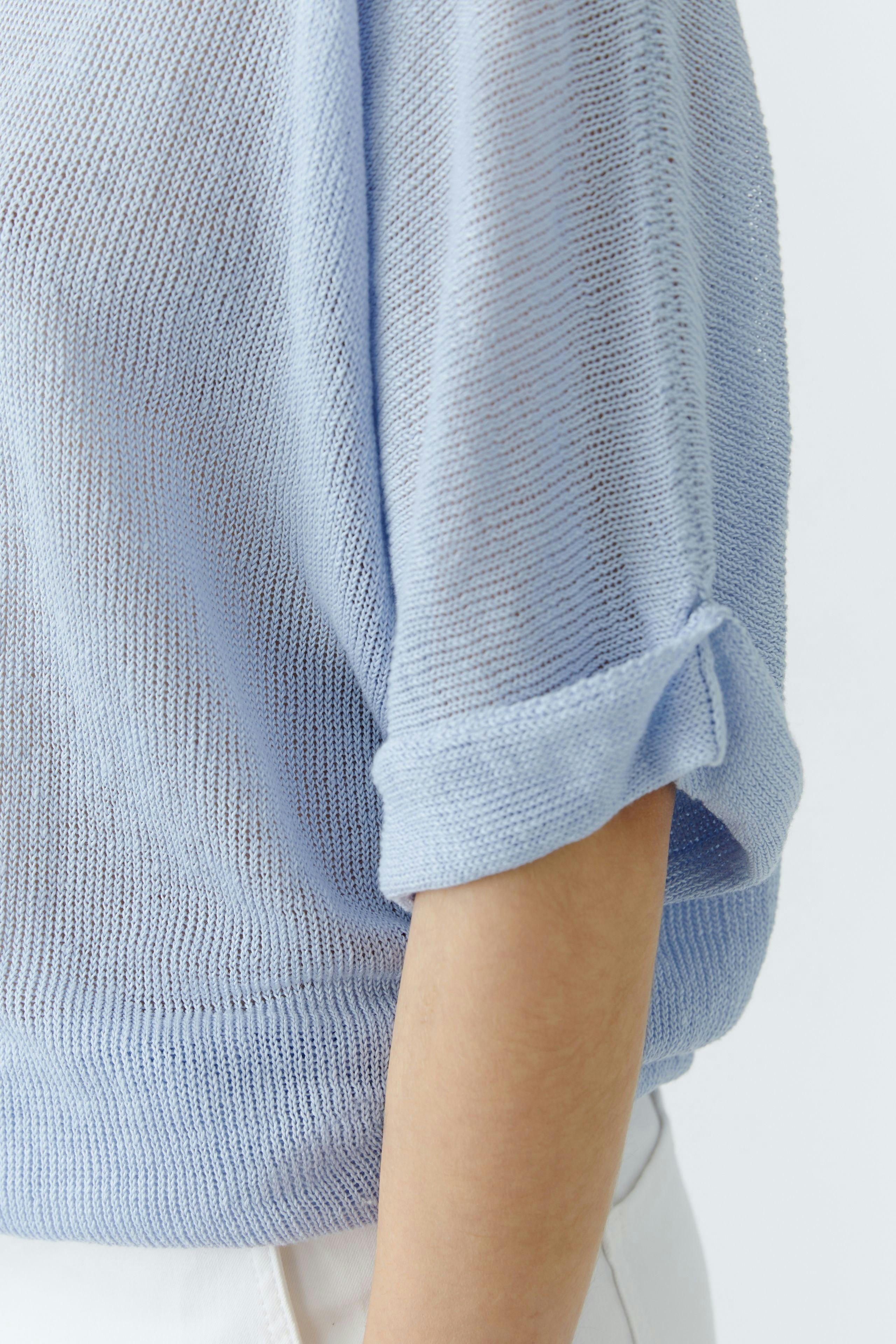 Light blue pullover: Woman in a loose-knit pullover with rolled sleeves, showcasing a relaxed style.