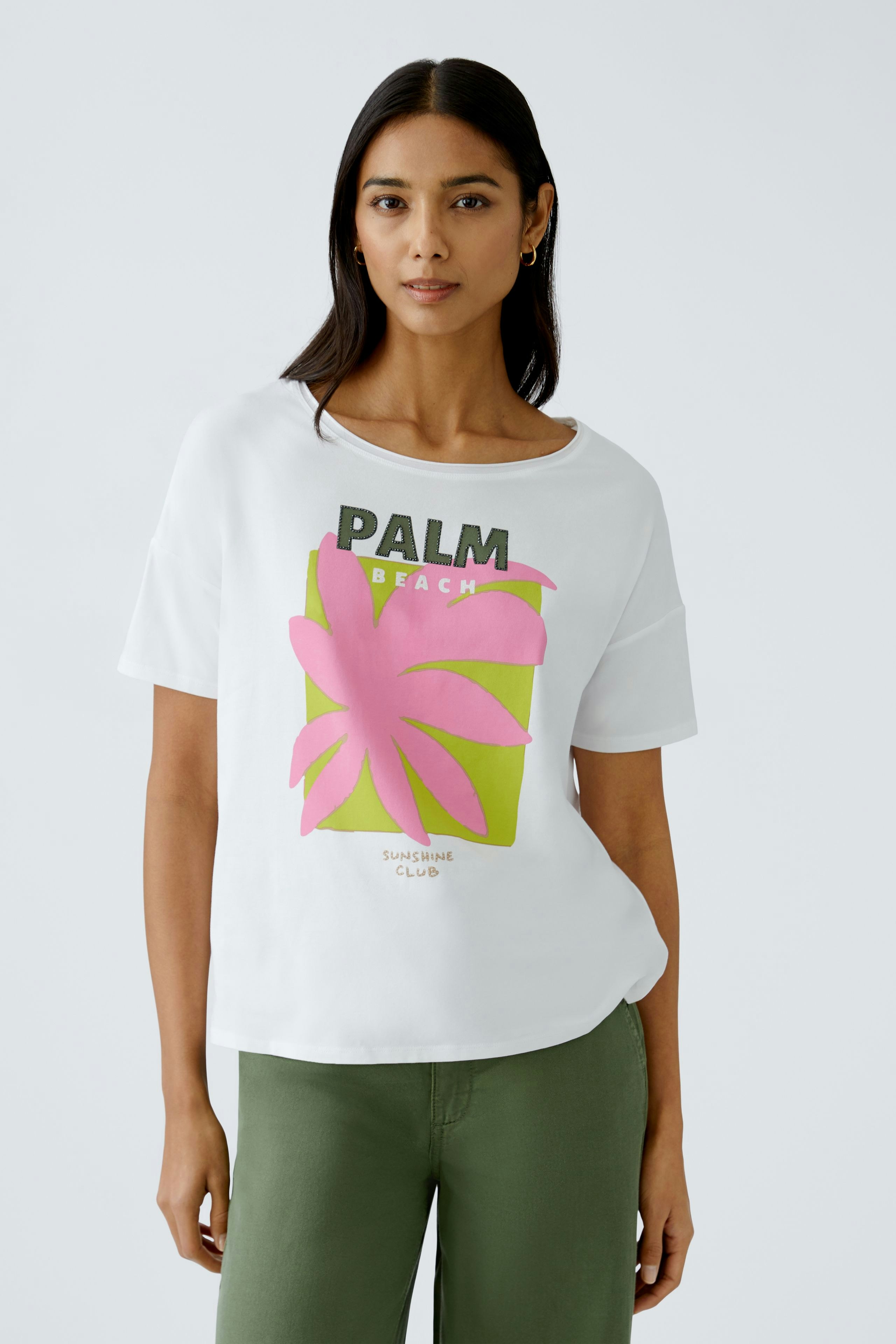 Stylish women's T-shirt: A woman in a white tee with a vibrant palm print, perfect for casual wear.