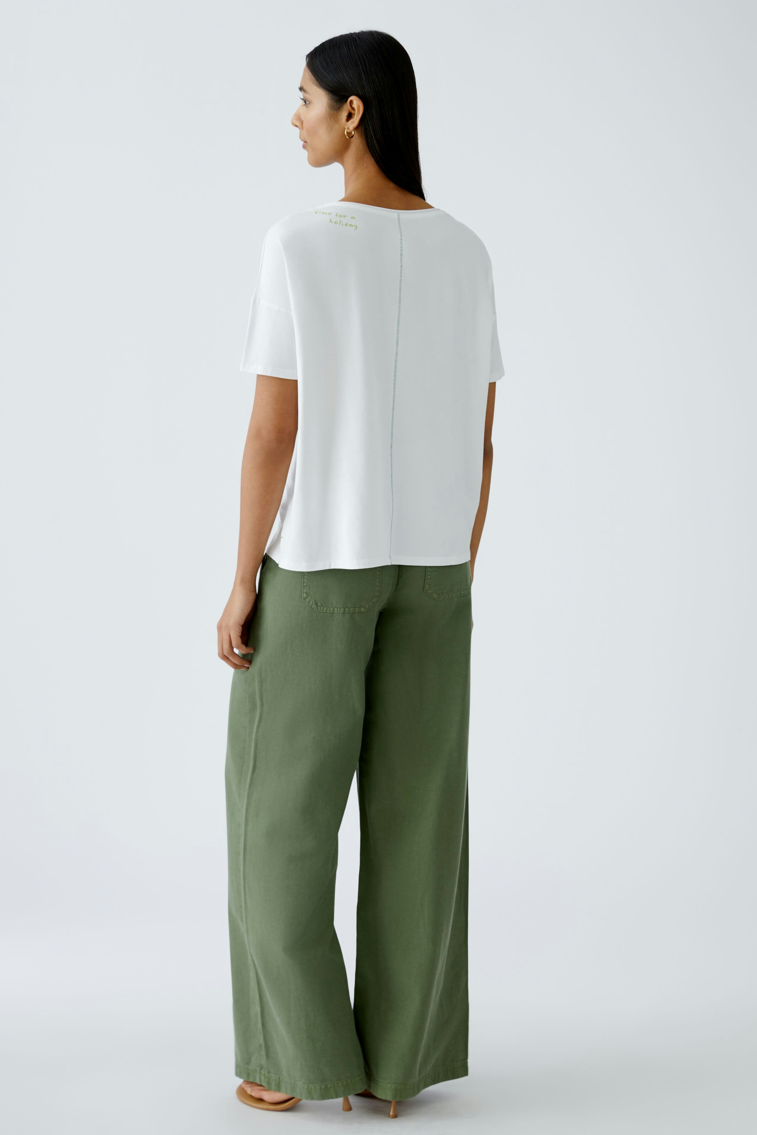 Stylish women's T-shirt: A woman in a white T-shirt paired with green wide-leg pants.