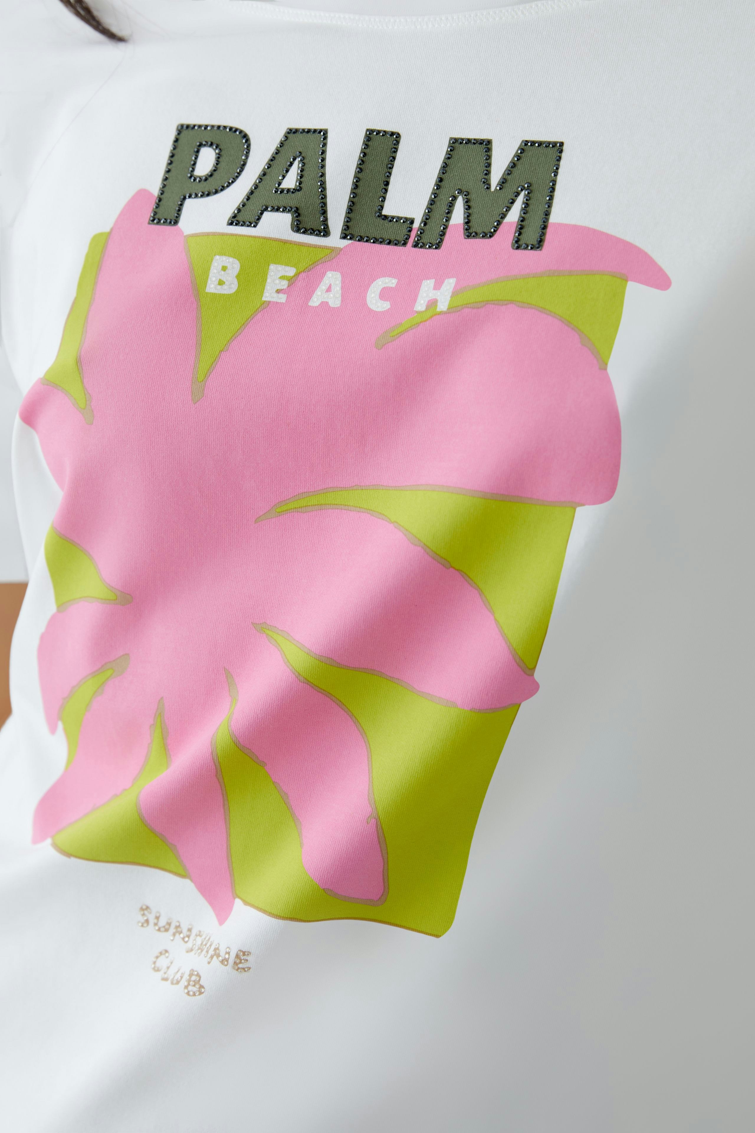 Stylish women's T-shirt: Close-up of a white tee featuring a vibrant palm graphic and bold text.