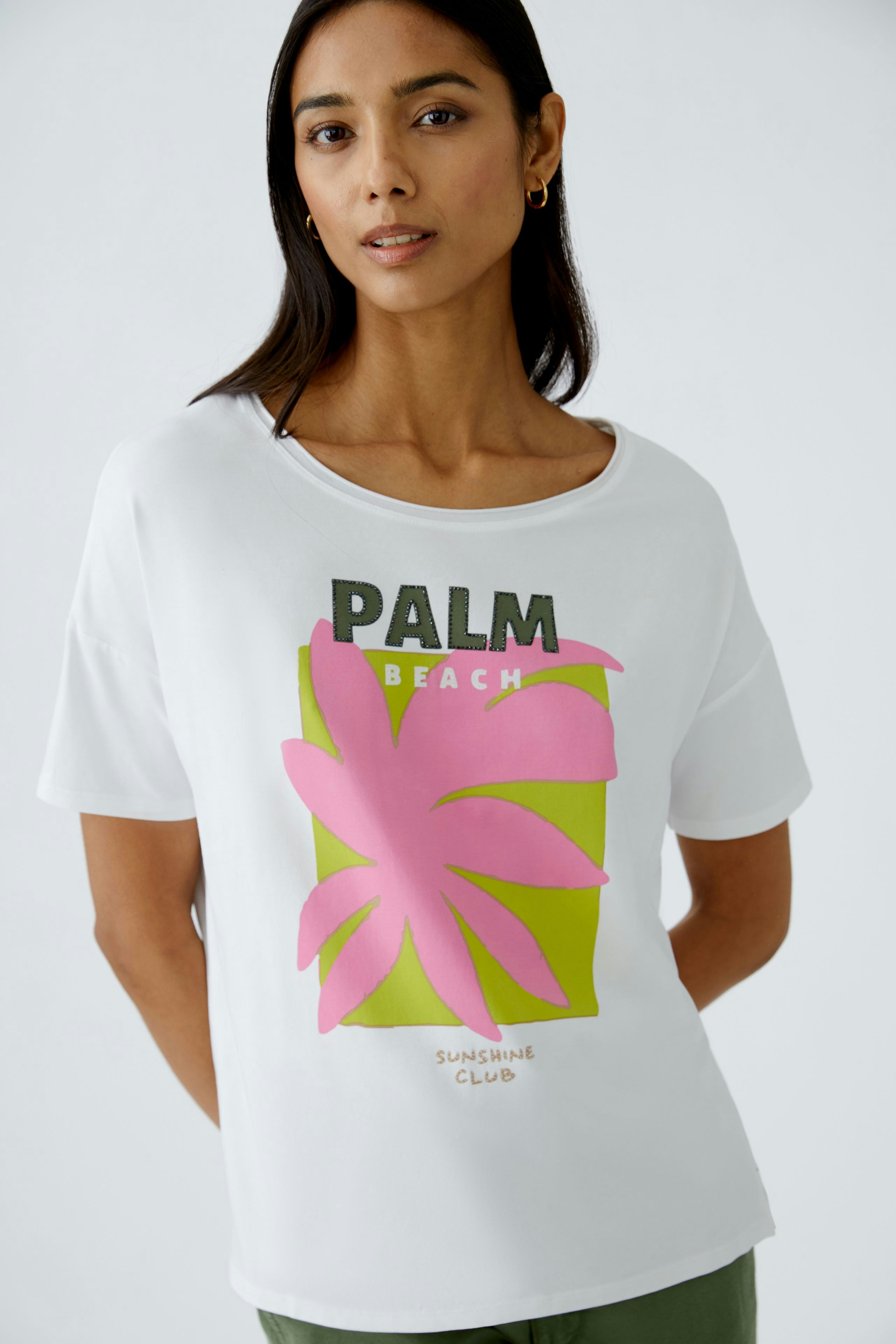 Stylish women's T-shirt: A woman in a white tee featuring a vibrant palm print and relaxed fit.