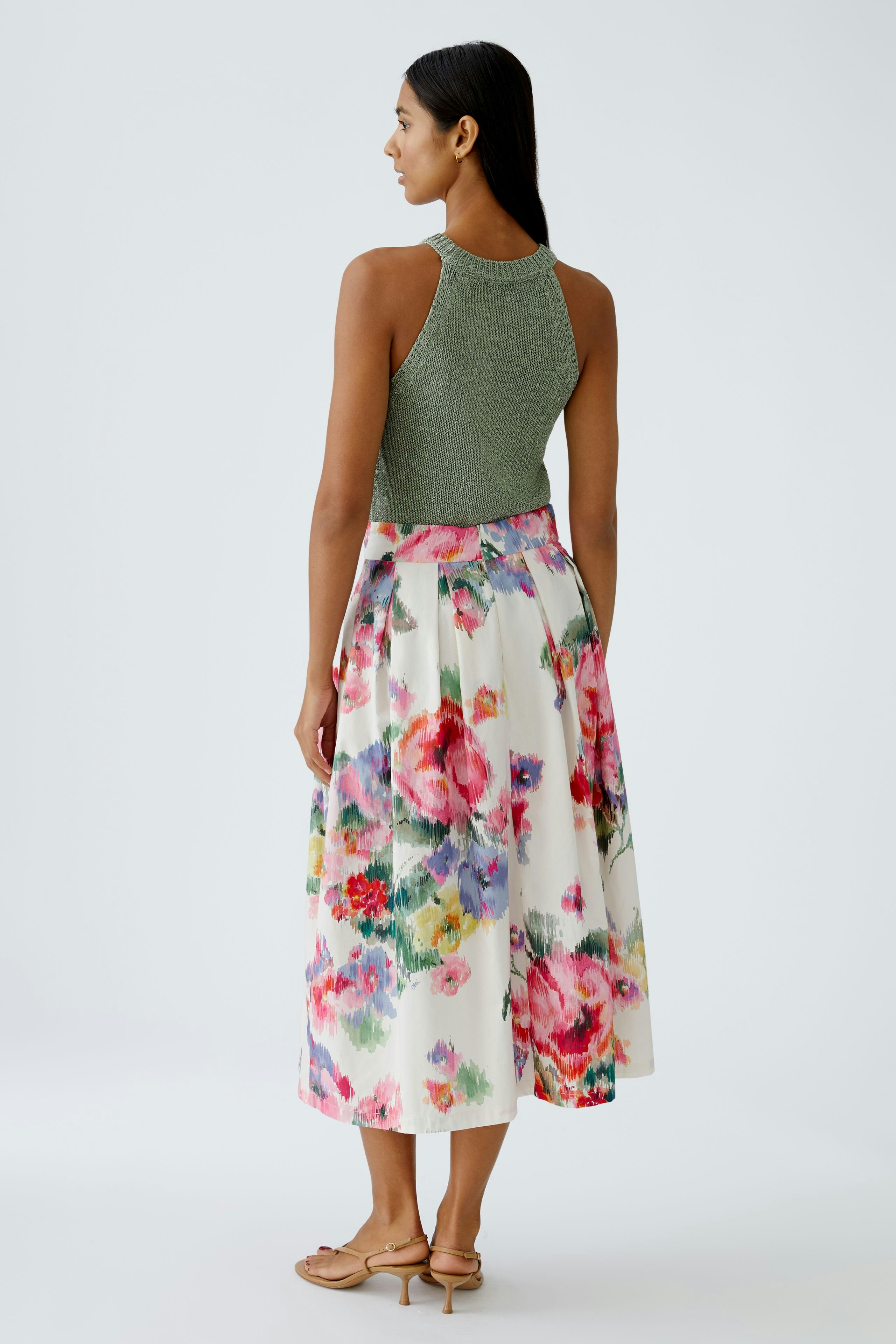 A-Linien-Rock: Frau in buntem, floralem Rock mit schickem Oberteil, elegant und feminin.