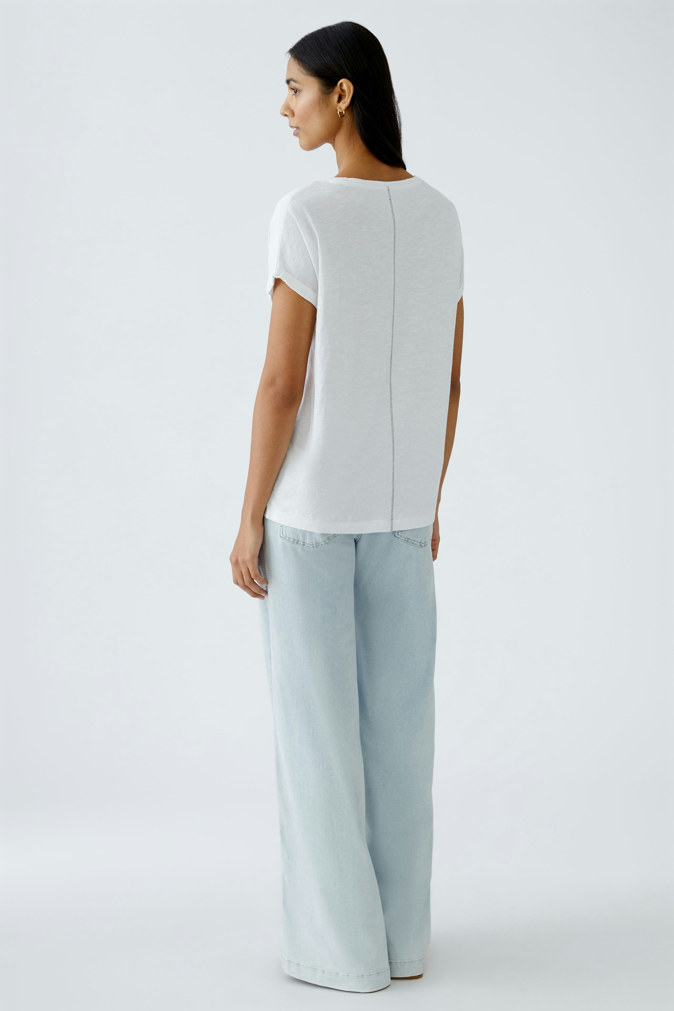 Elegantes Damen-T-Shirt: Frau in weißem T-Shirt mit lässigem Schnitt und dezentem Design von hinten.