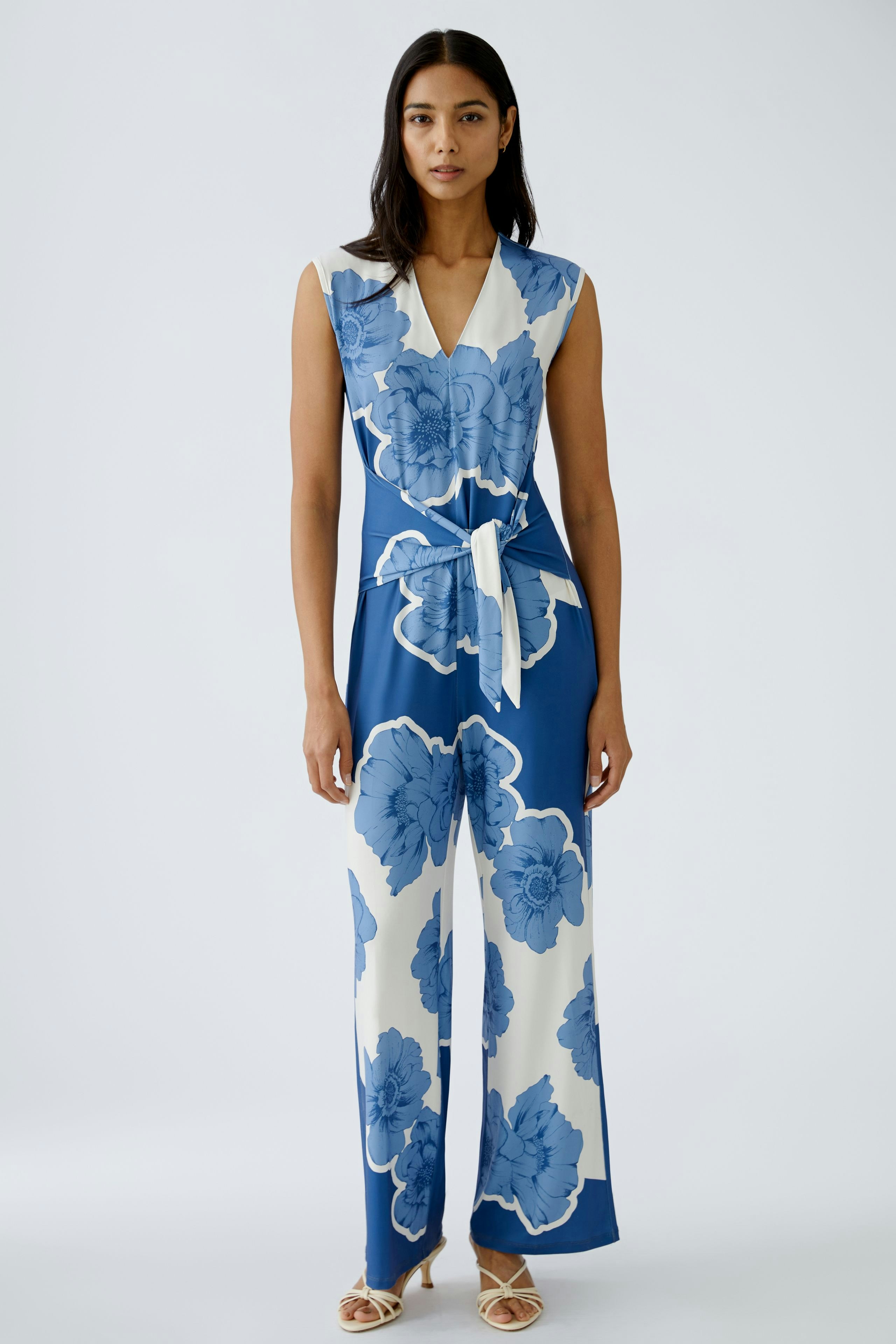 Stylish women's jumpsuit: A woman in a blue floral jumpsuit with a tied waist, exuding elegance.