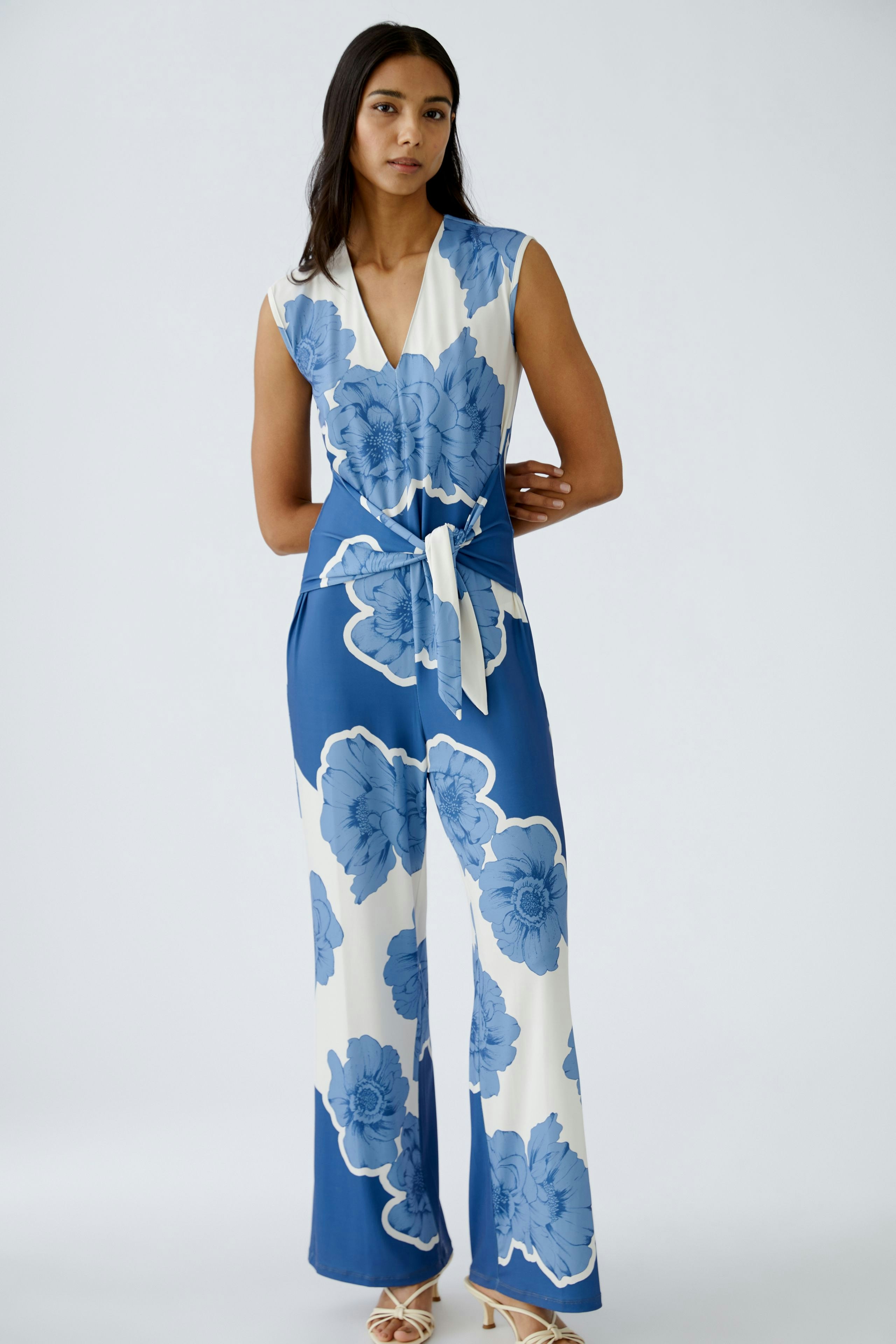 Stylish women's jumpsuit: A woman in a blue floral jumpsuit with a tied waist, exuding elegance.