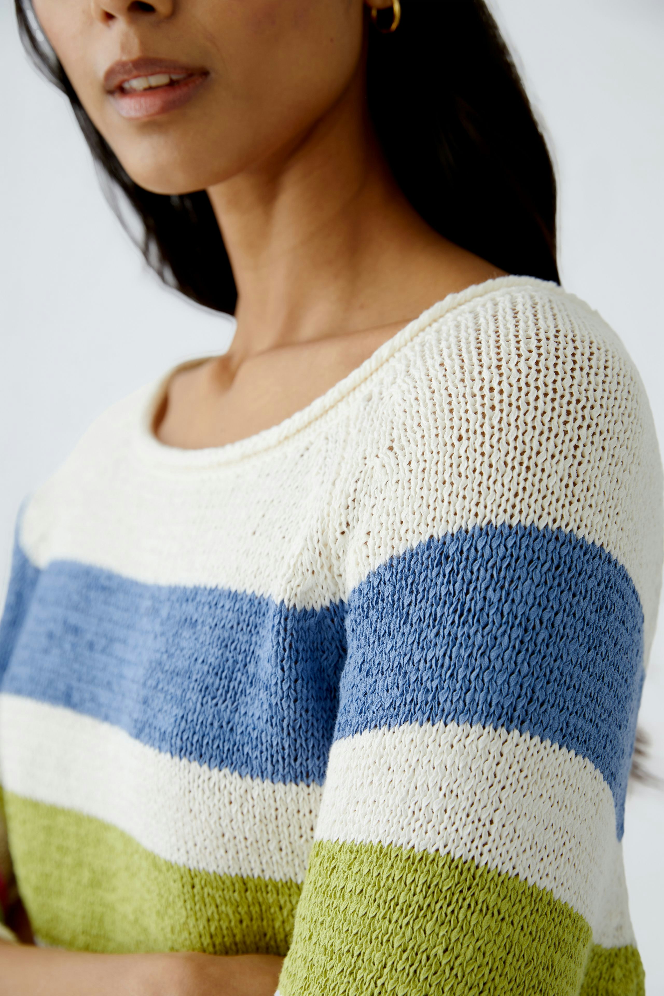 Stylish women's pullover: Close-up of a woman in a striped knit pullover with blue, green, and cream colors.