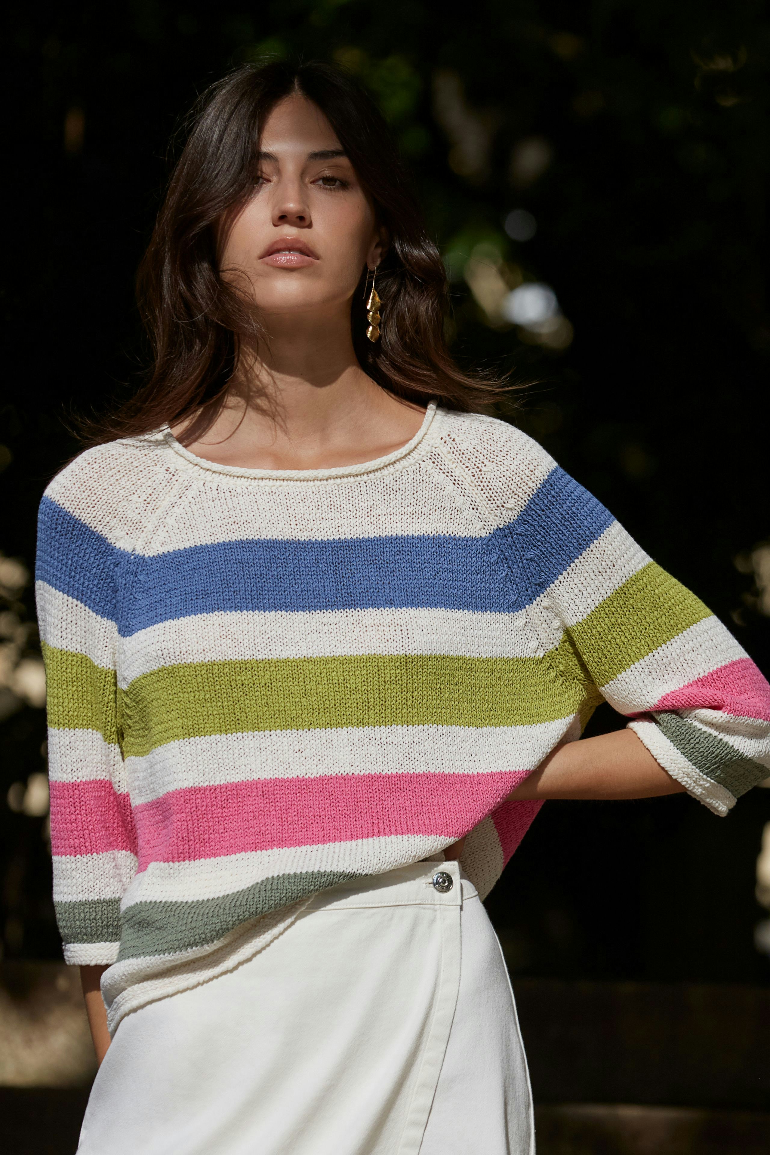 Stylish women's pullover: A woman in a colorful striped pullover, exuding confidence and elegance.