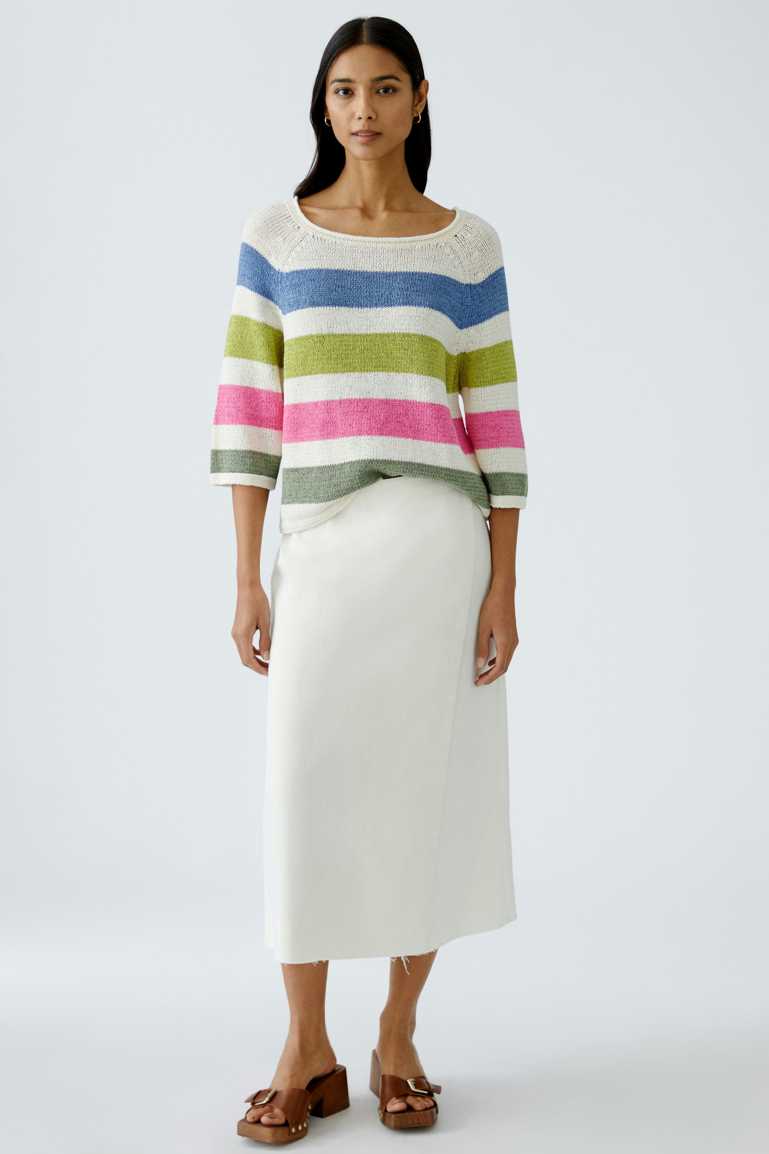 Stylish women's pullover: A woman in a colorful striped pullover paired with a white skirt.
