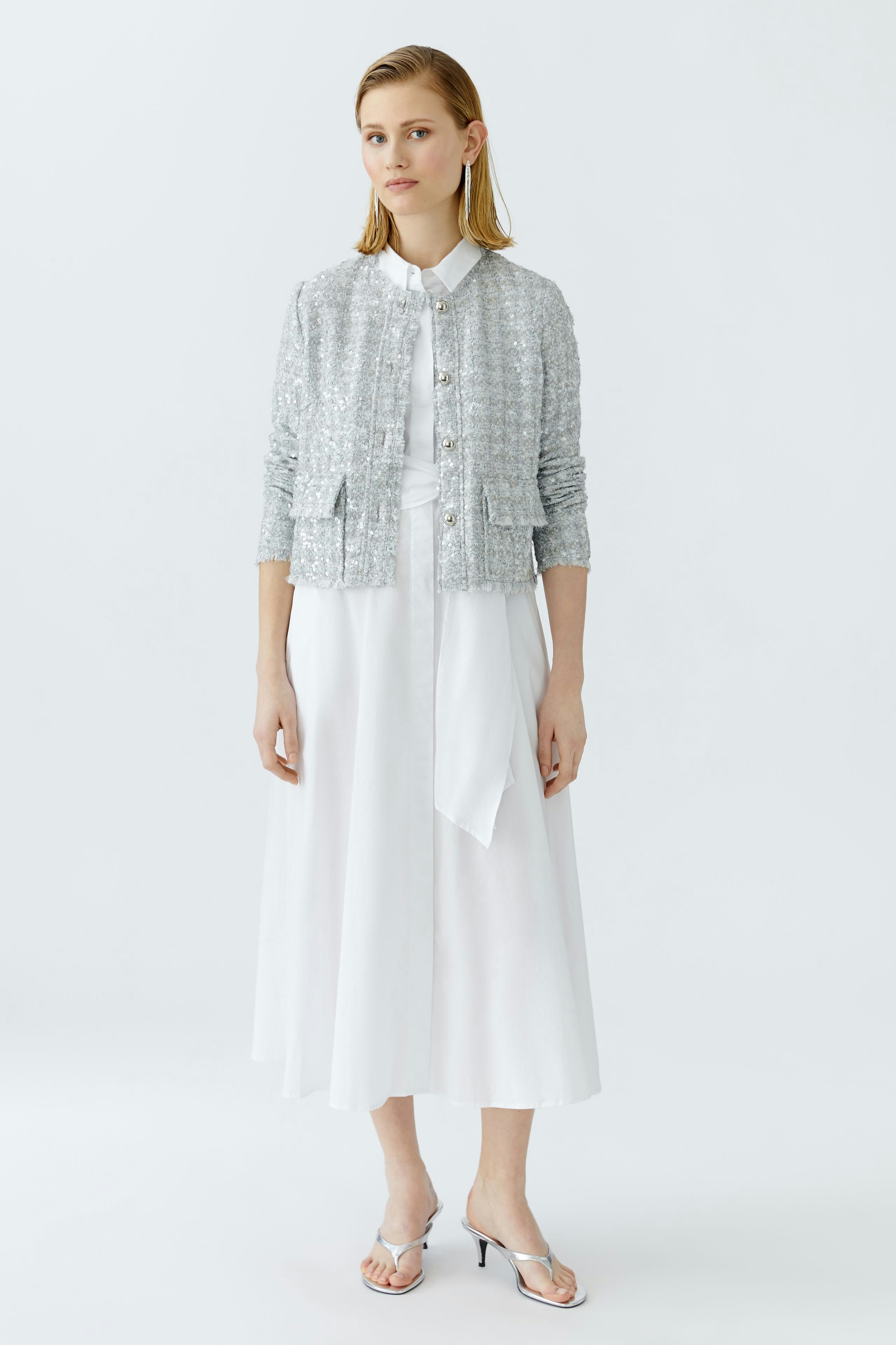 Moderne Damen-Jacke: Frau in glitzernder, silberner Jacke mit Knöpfen und lässigem Look.