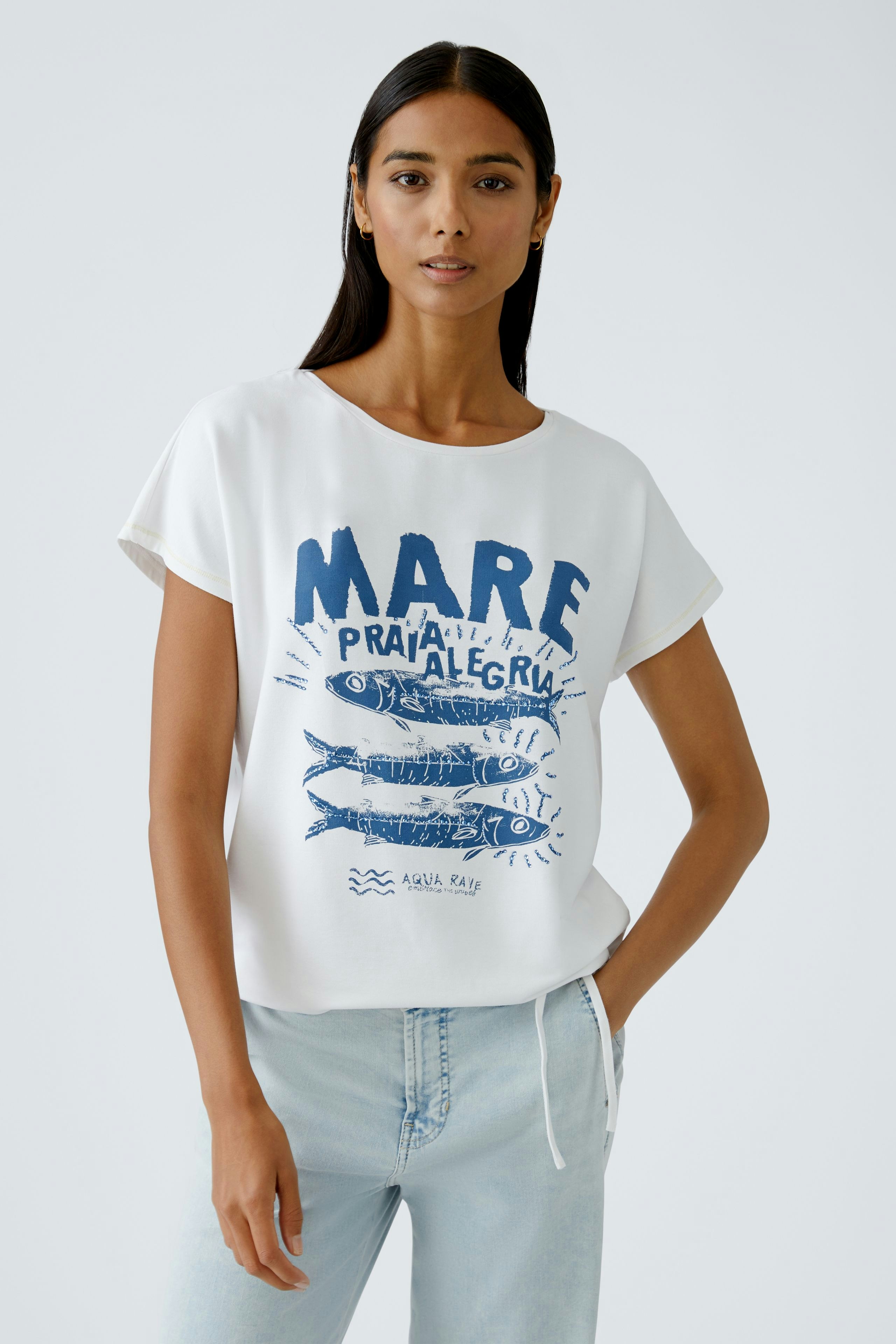Damen-T-Shirt: Frau in weißem Shirt mit blauem Druck und lässigem Schnitt, ideal für den Alltag.
