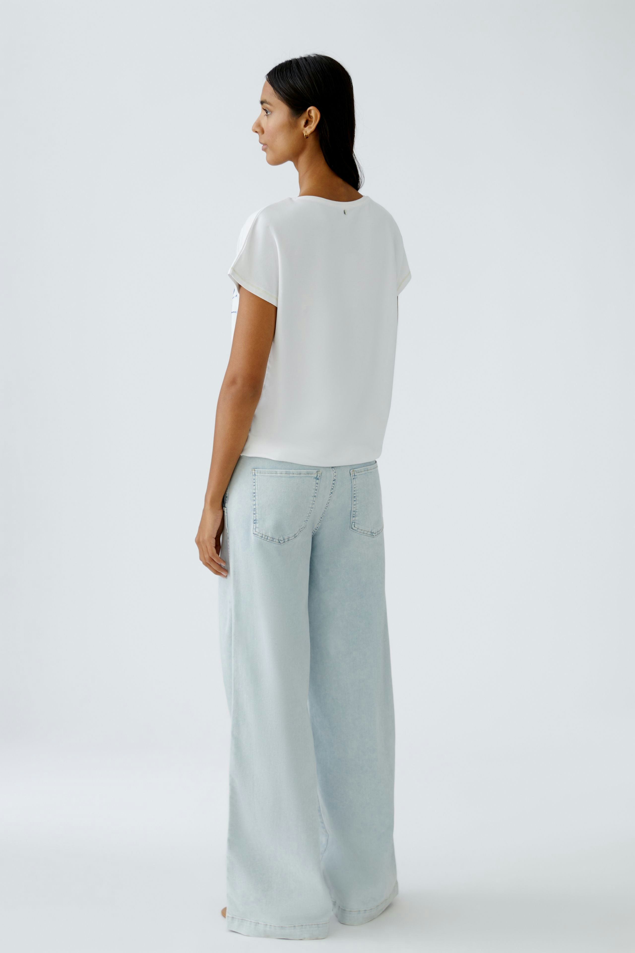 Damen-T-Shirt: Frau in weißem, lässigem T-Shirt mit kurzen Ärmeln und lockerer Passform von hinten.